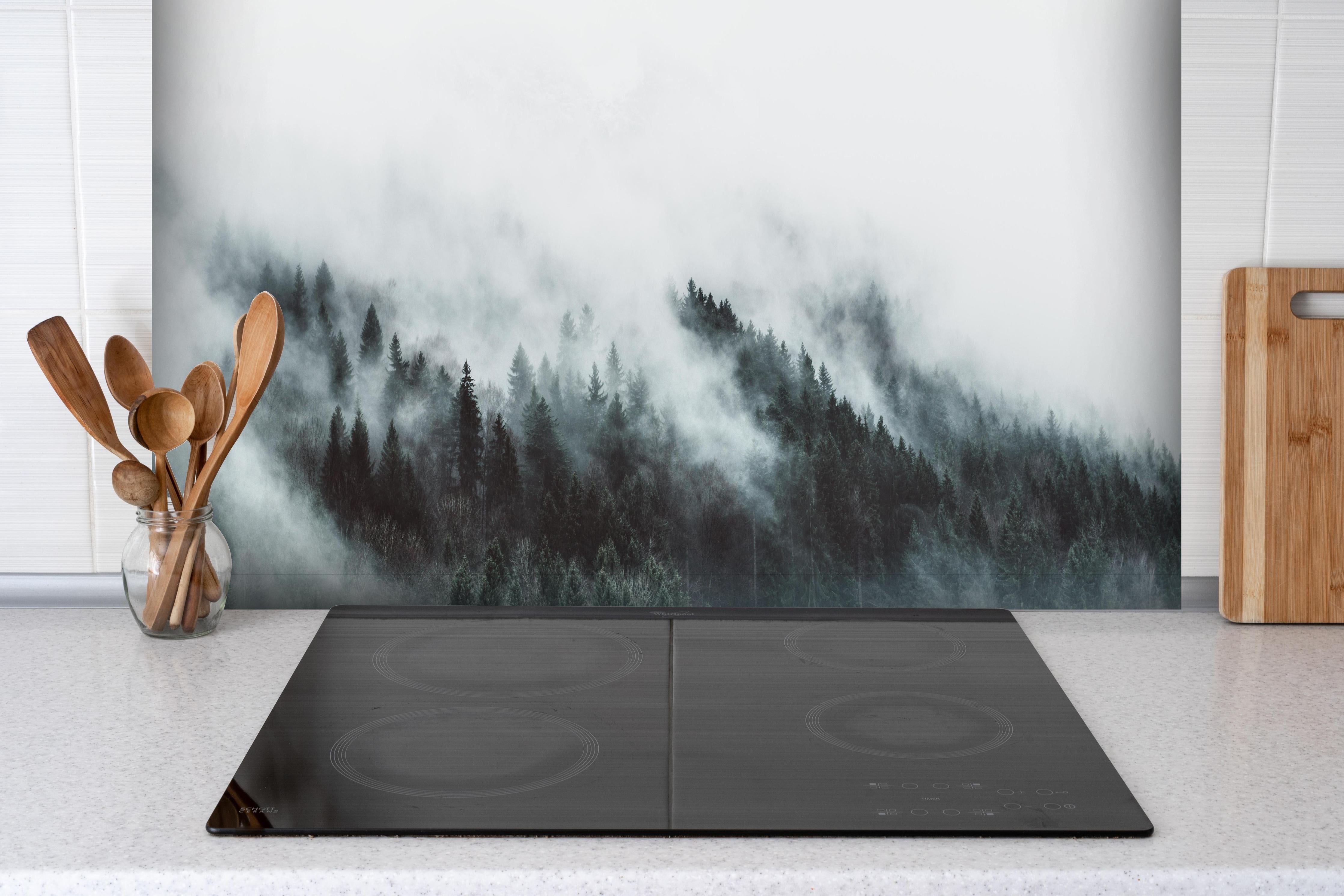 Spritzschutz - Mystischer Nebelwald in Grau-Weiß Nuancen hinter einem Cerankochfeld zwischen Holz-Kochutensilien