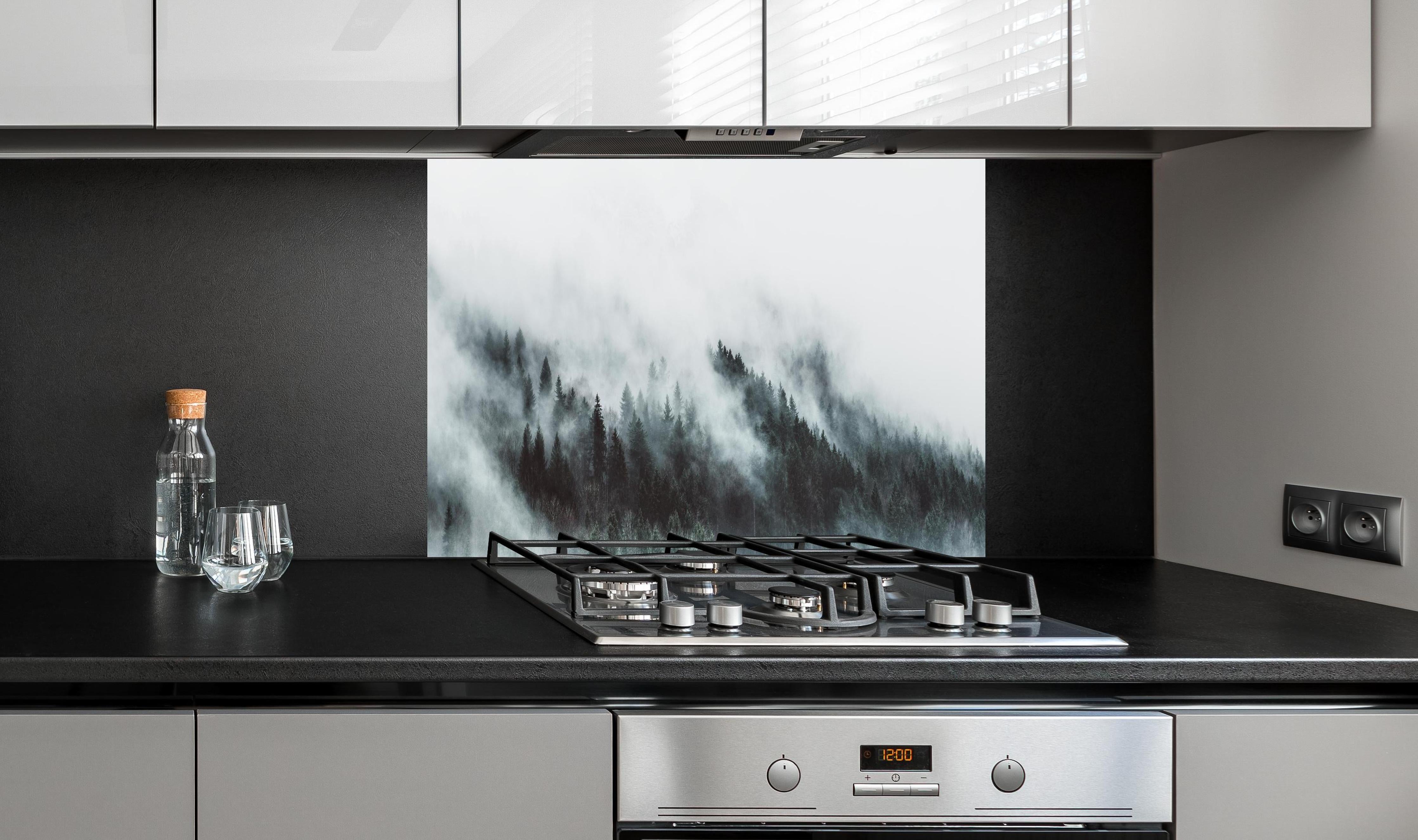 Spritzschutz - Mystischer Nebelwald in Grau-Weiß Nuancen hinter einem Cerankochfeld zwischen Holz-Kochutensilien