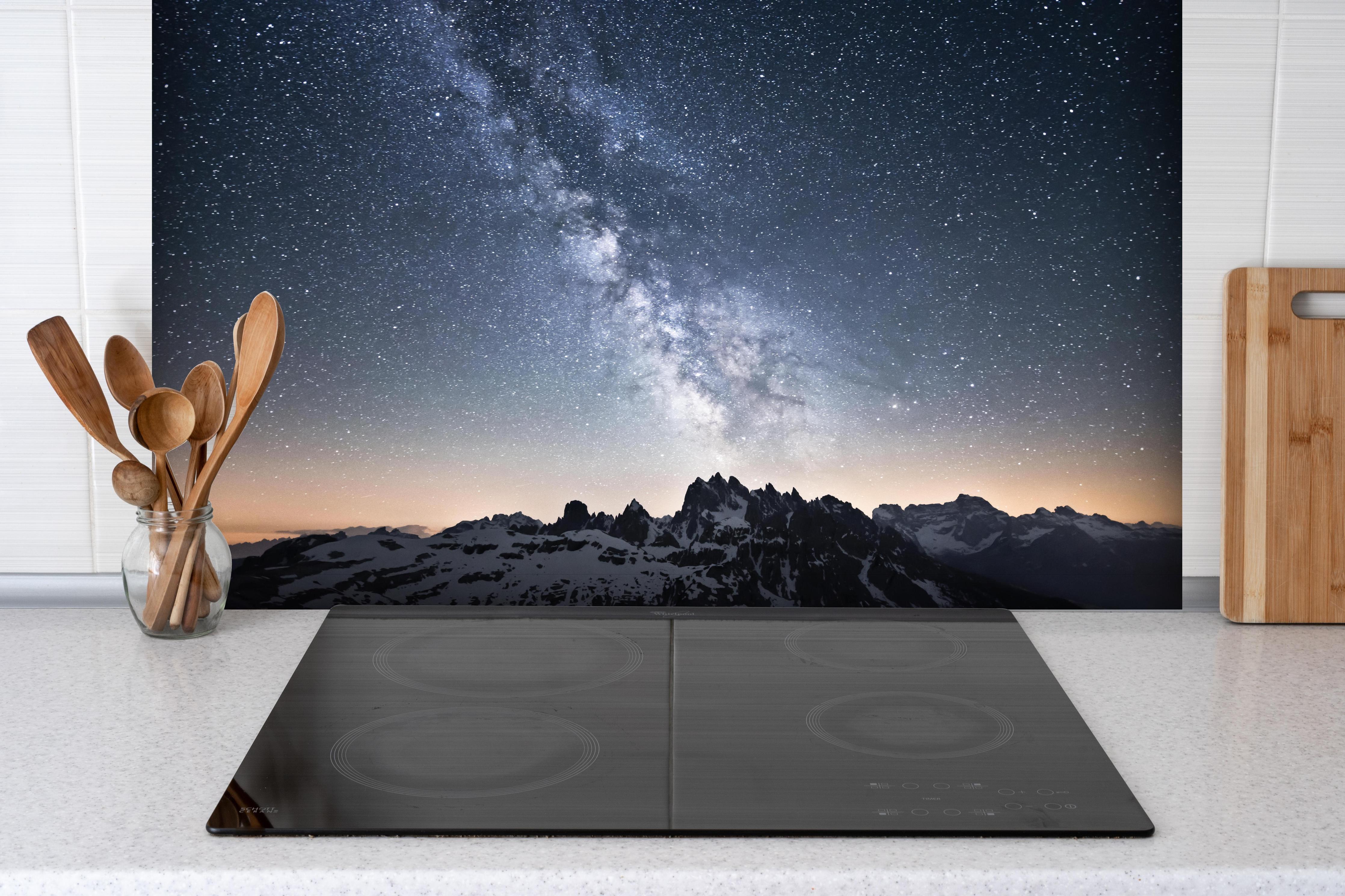 Spritzschutz - Nachthimmel Sterne Schneeberge Panorama hinter einem Cerankochfeld zwischen Holz-Kochutensilien