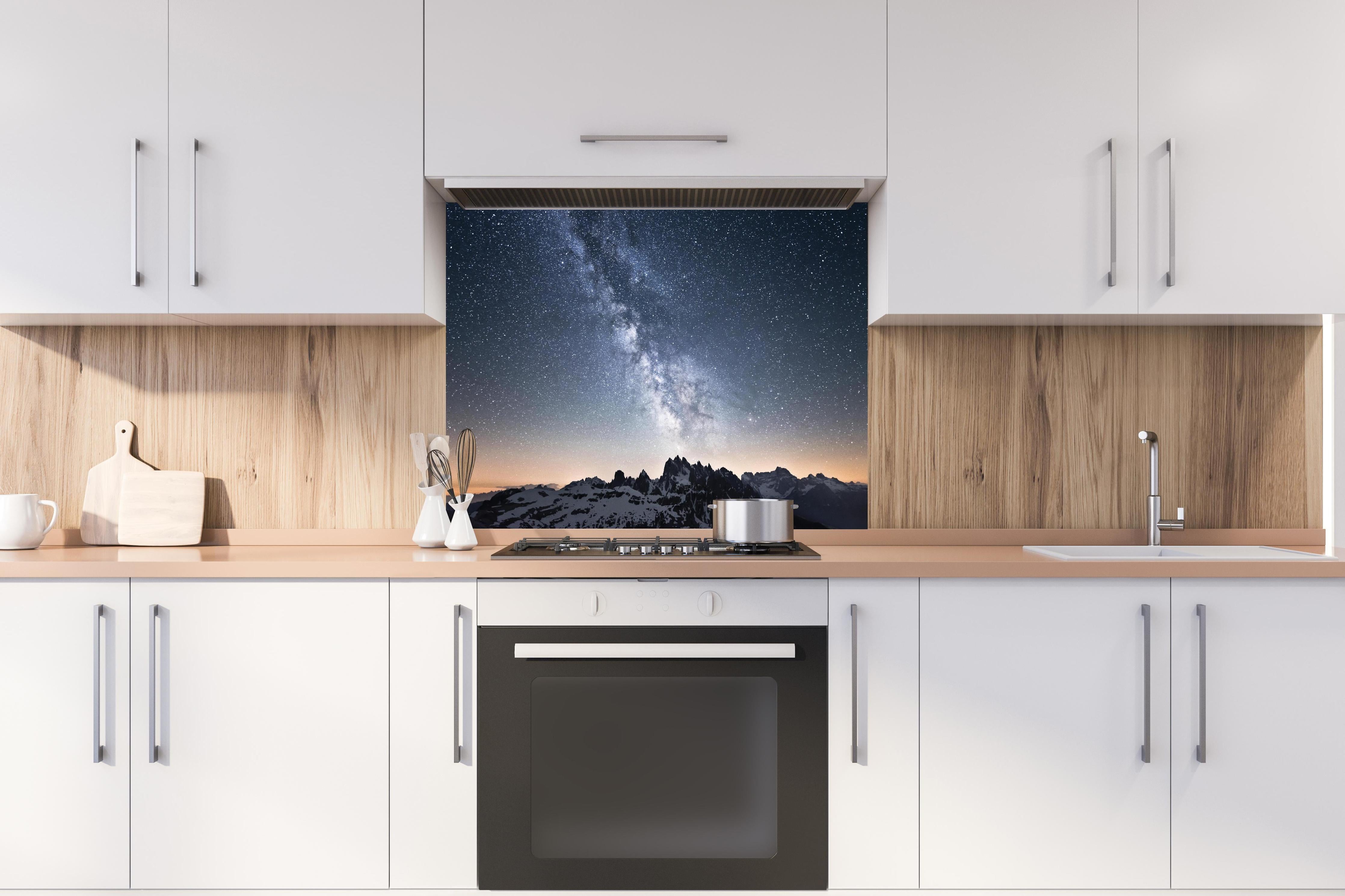 Spritzschutz - Nachthimmel Sterne Schneeberge Panorama hinter einem Cerankochfeld zwischen Holz-Kochutensilien
