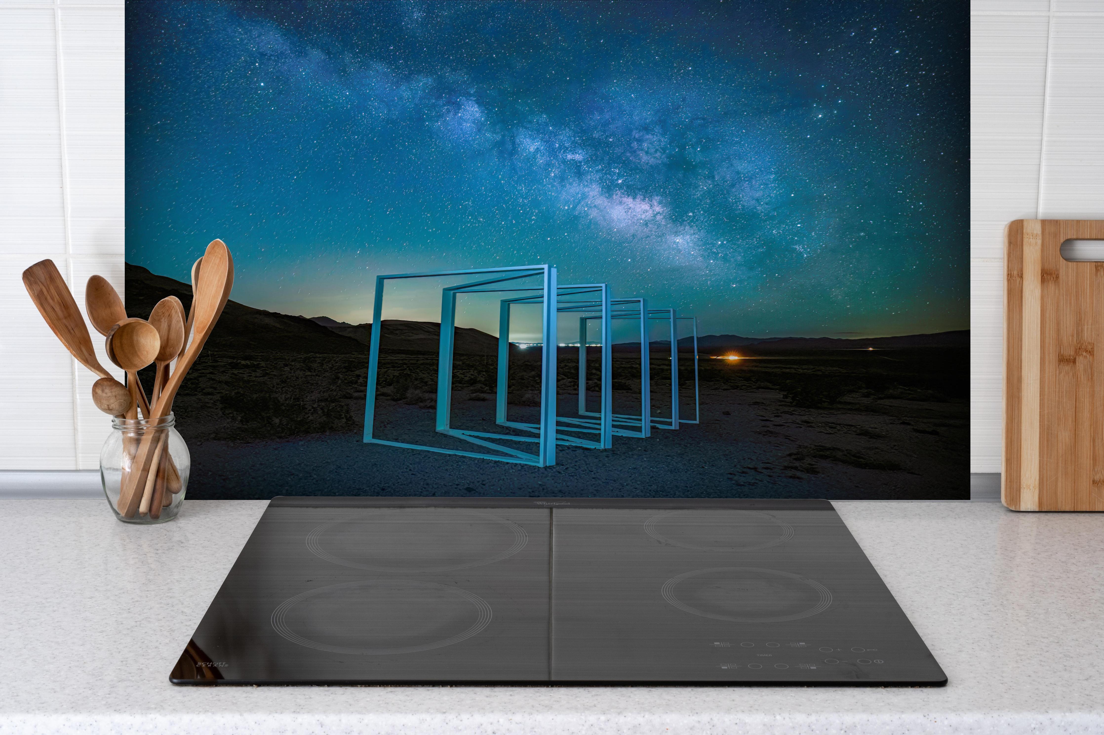 Spritzschutz - Nächtliche Landschaft hinter einem Cerankochfeld zwischen Holz-Kochutensilien