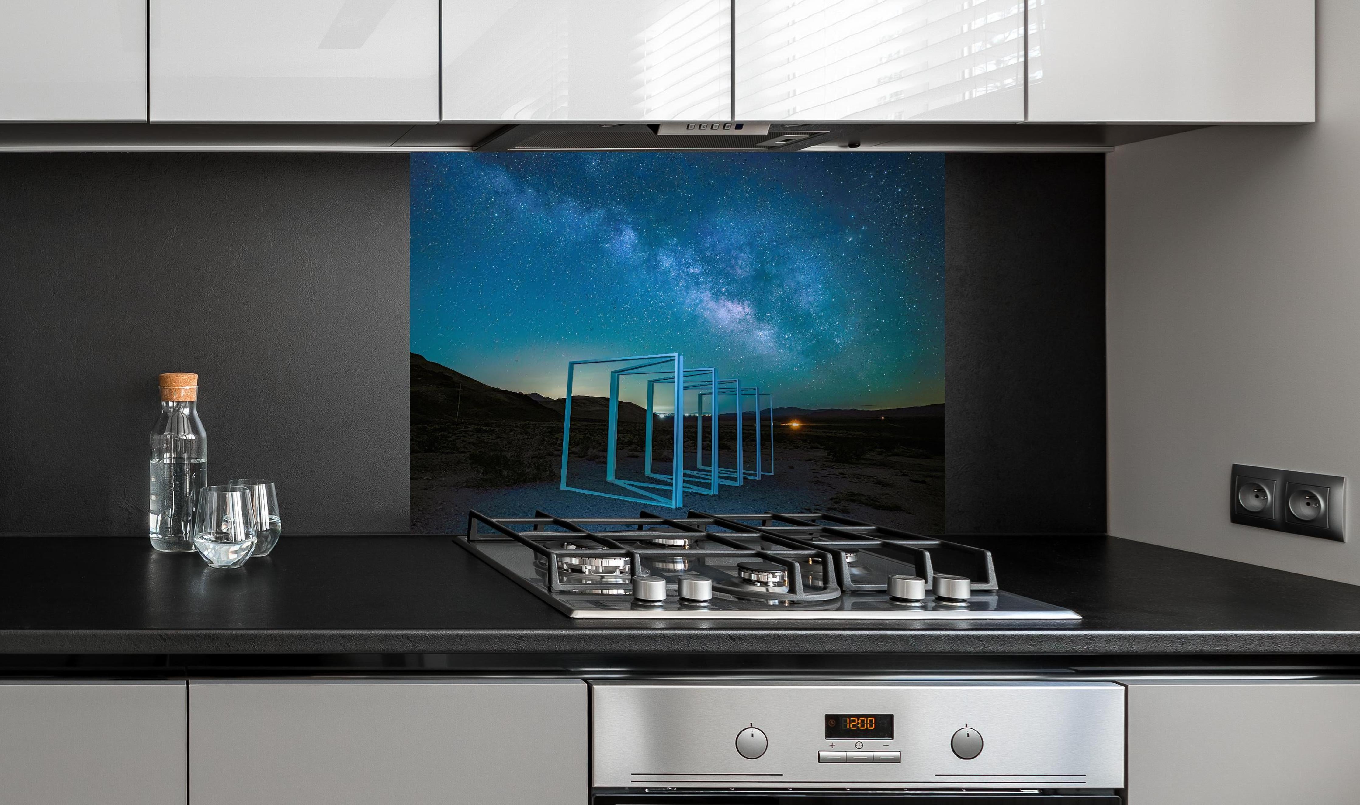 Spritzschutz - Nächtliche Landschaft hinter einem Cerankochfeld zwischen Holz-Kochutensilien