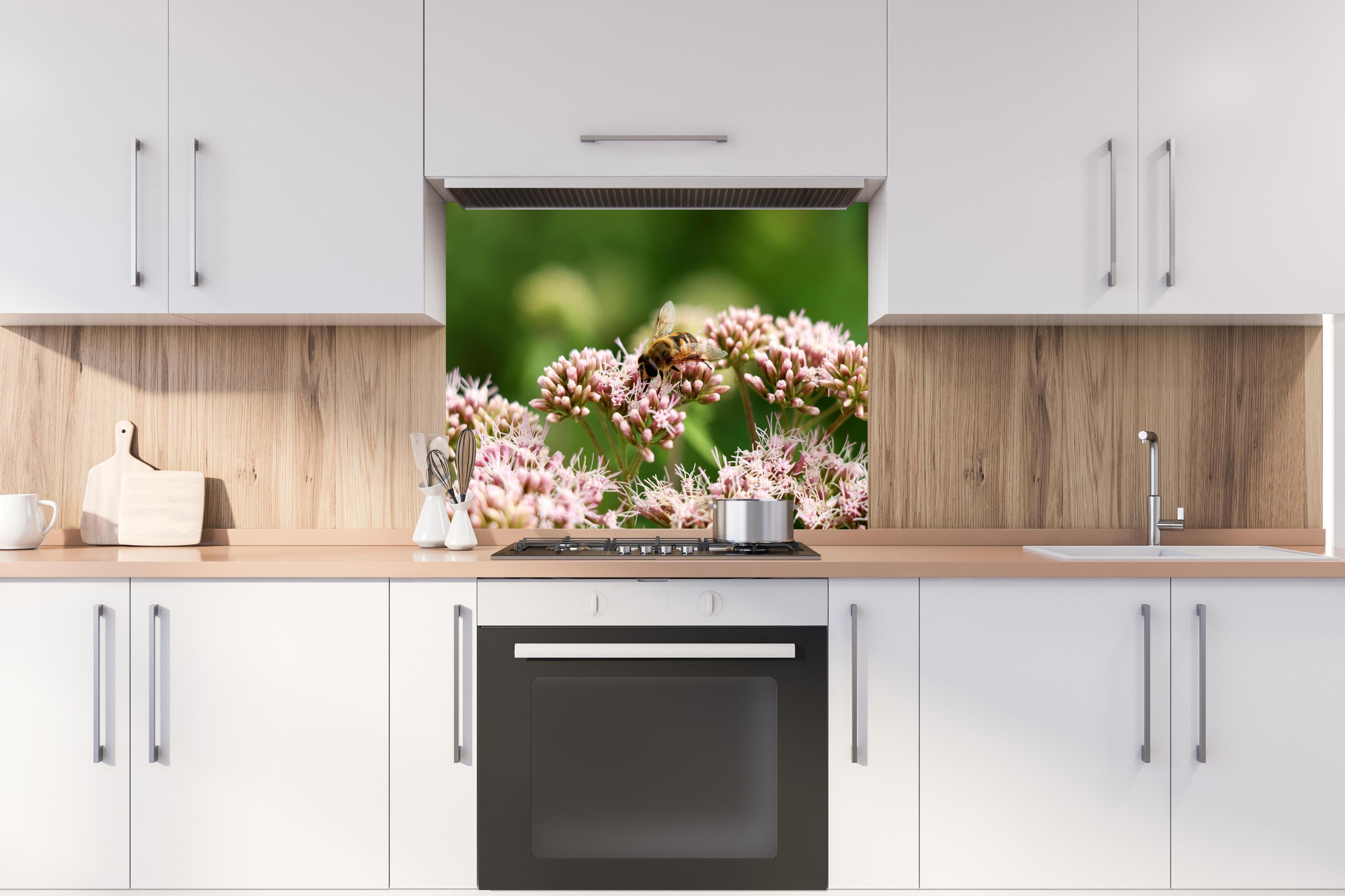 Spritzschutz - Nahaufnahme Biene Rosa Blütenpracht hinter einem Cerankochfeld zwischen Holz-Kochutensilien