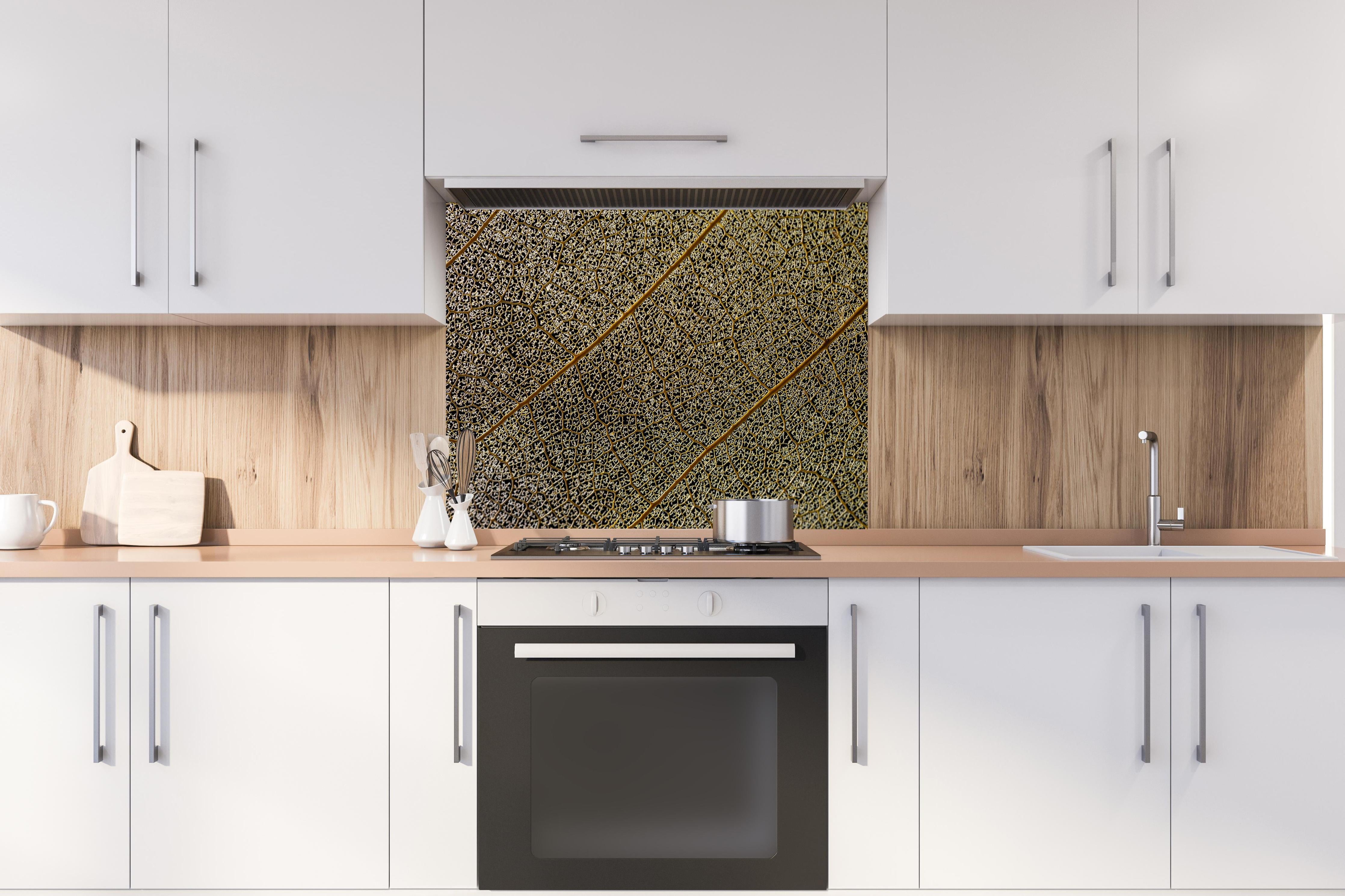 Spritzschutz - Nahaufnahme Blattstruktur mit Adern hinter einem Cerankochfeld zwischen Holz-Kochutensilien