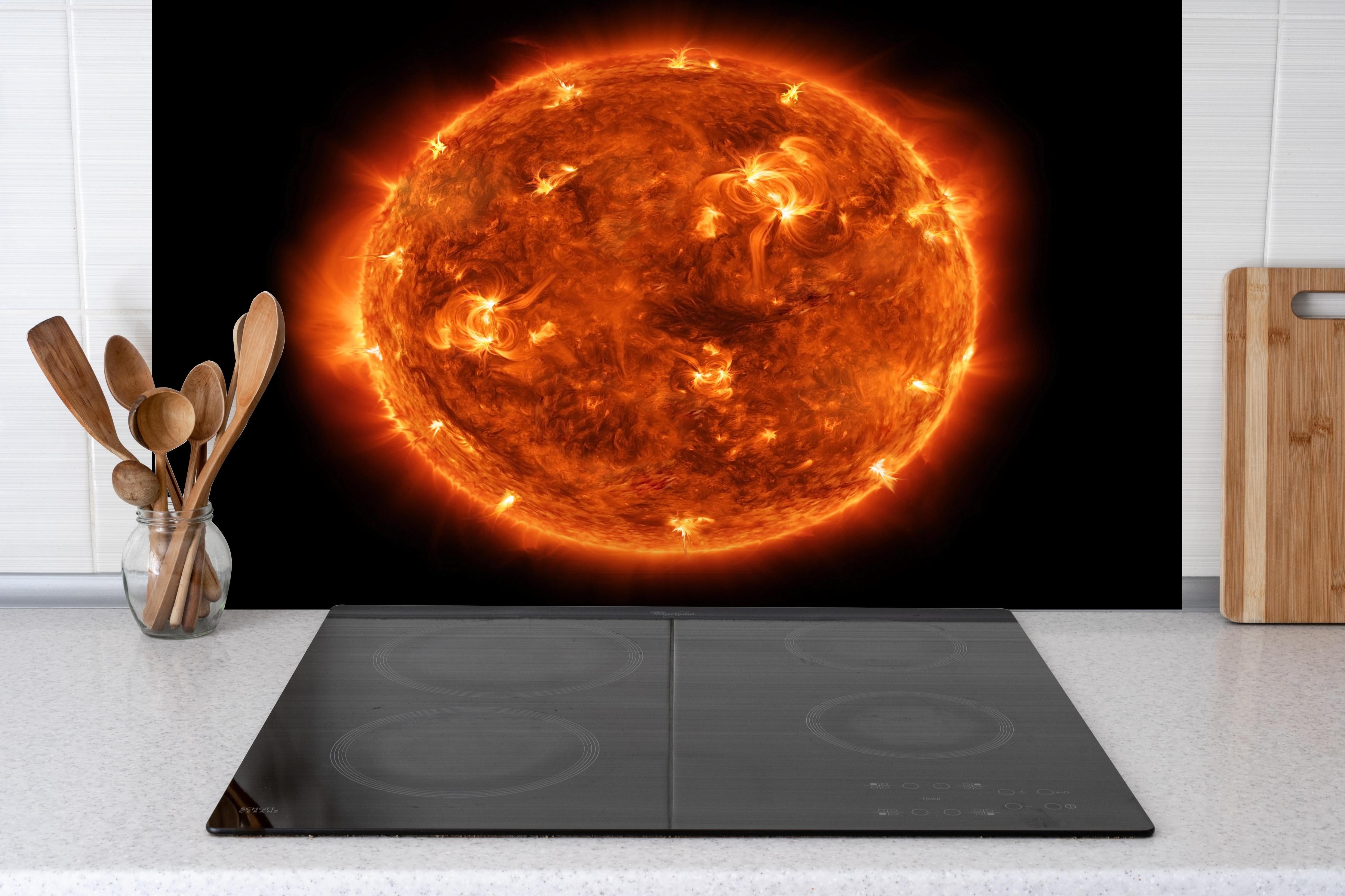 Spritzschutz - Nahaufnahme der Sonne hinter einem Cerankochfeld zwischen Holz-Kochutensilien