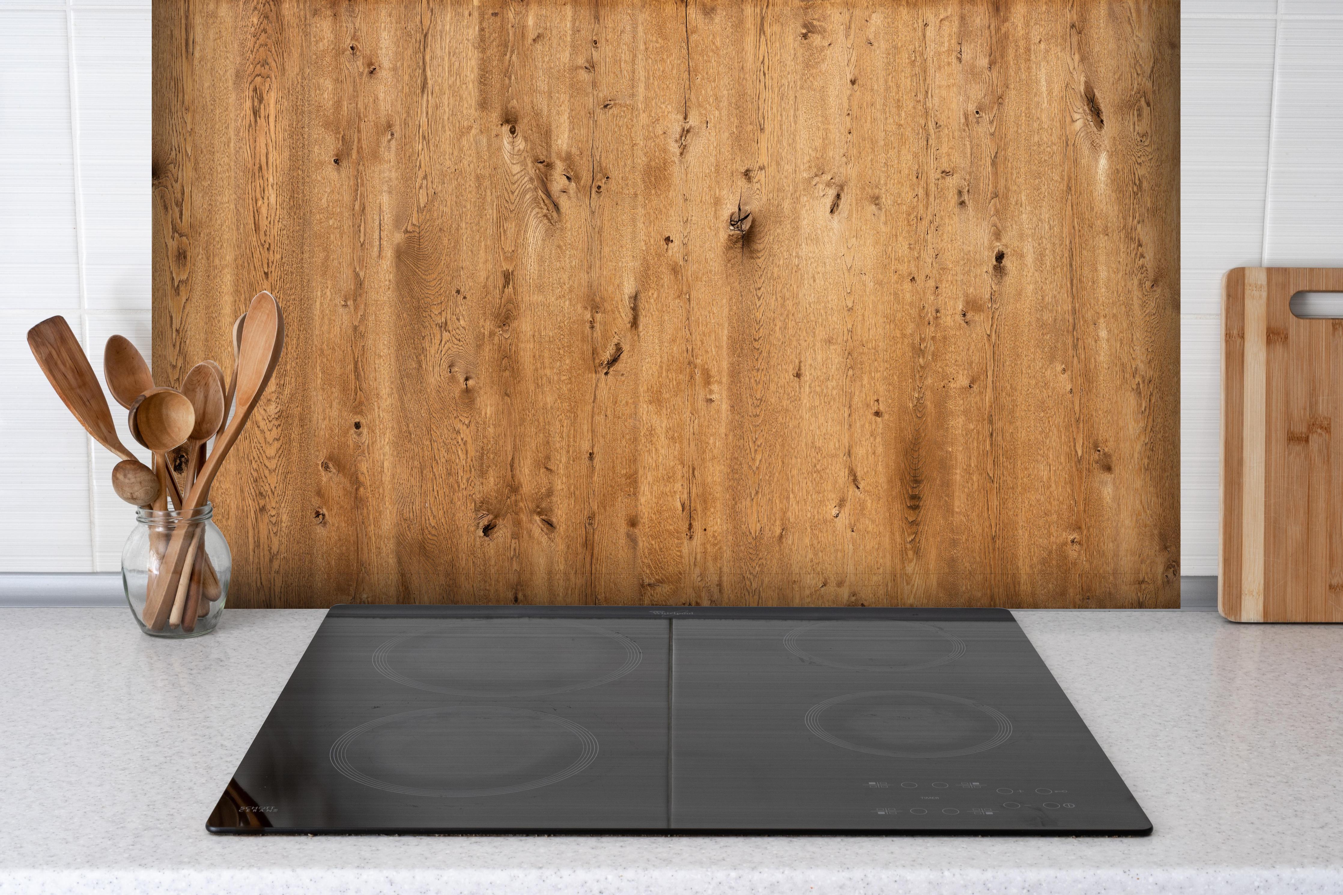 Spritzschutz - Natürliche Eichenholz-Struktur hinter einem Cerankochfeld zwischen Holz-Kochutensilien
