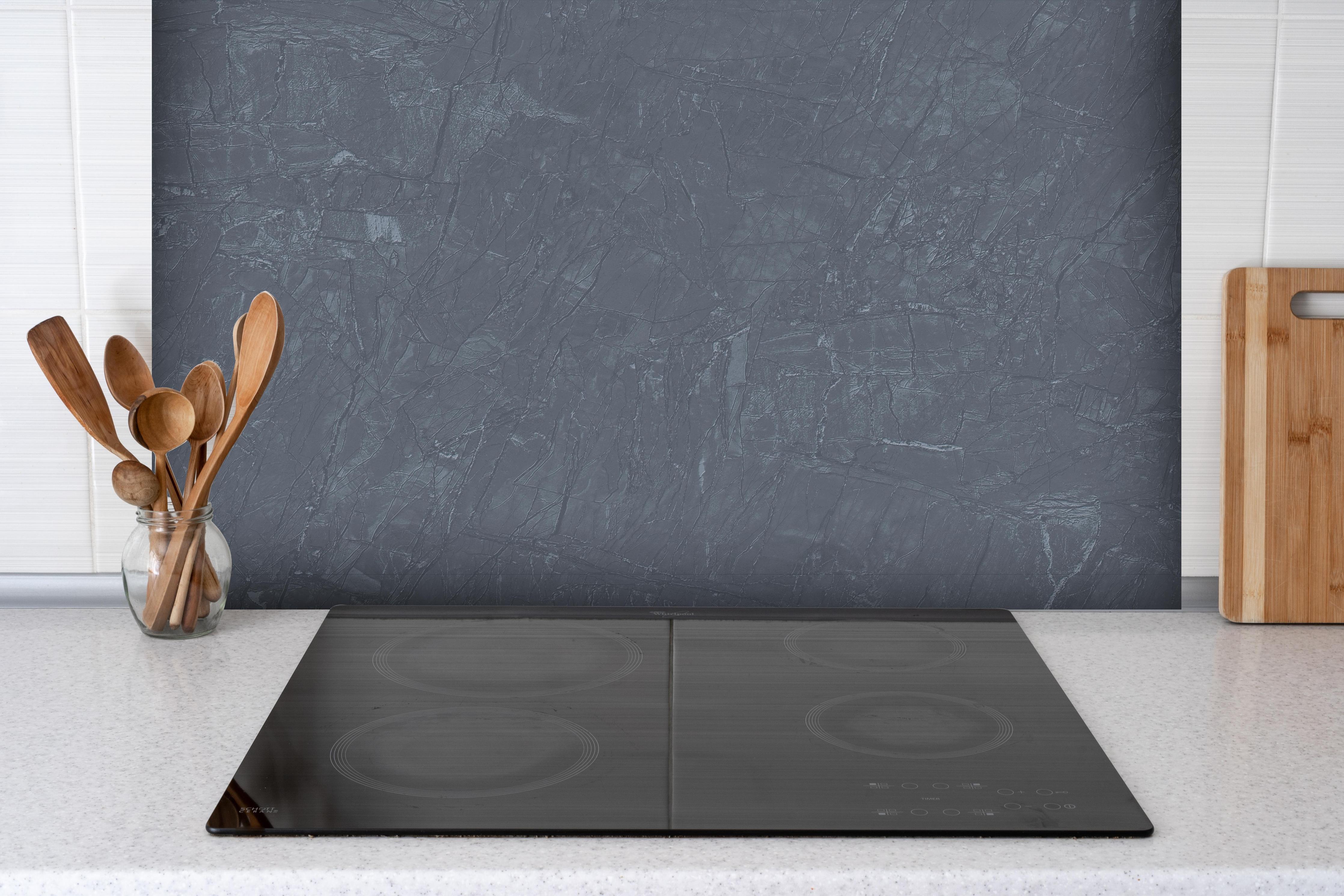 Spritzschutz - Natürliche Mamortextur hinter einem Cerankochfeld zwischen Holz-Kochutensilien