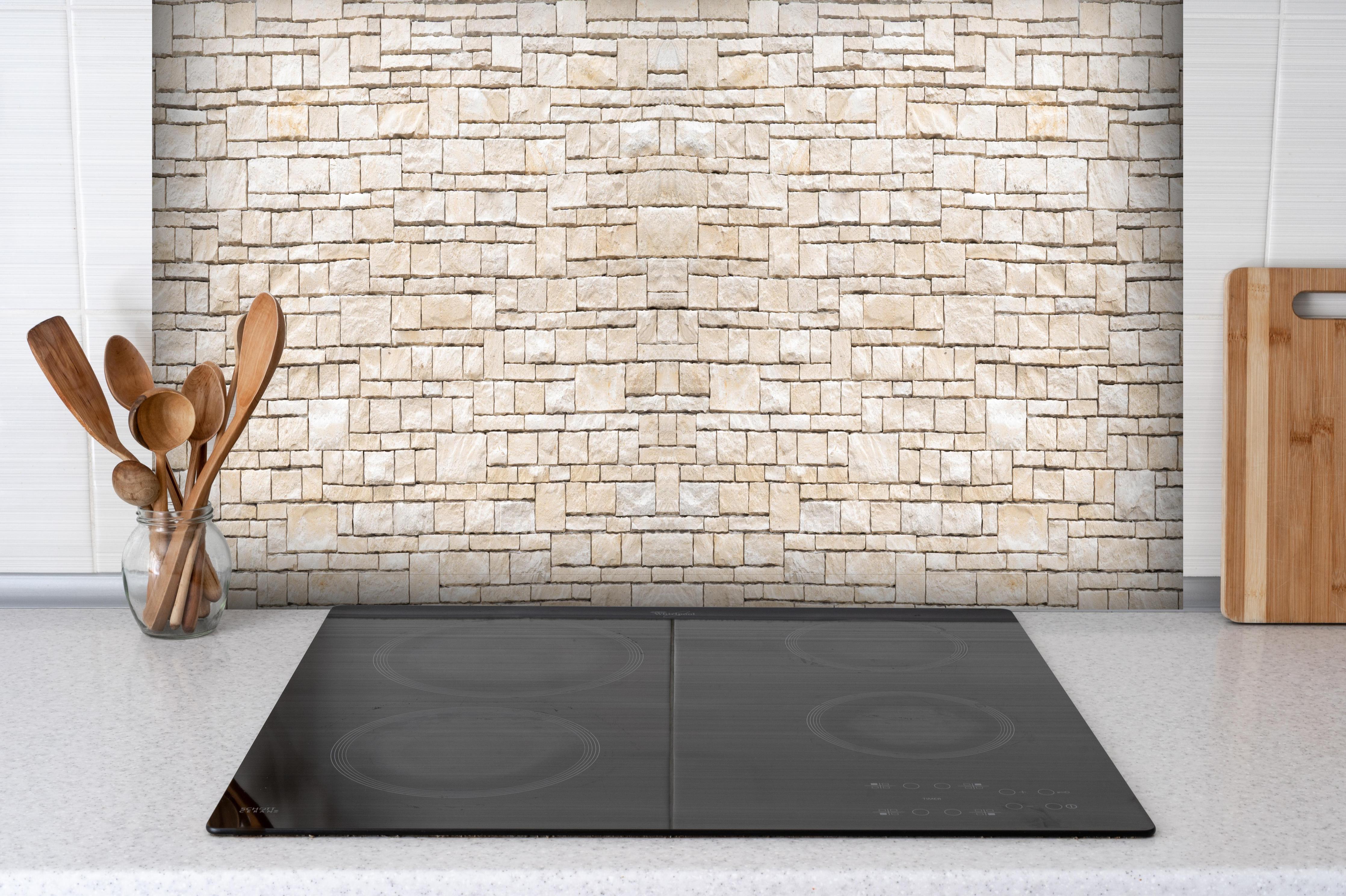 Spritzschutz - Natürliche beige Ziegelwand hinter einem Cerankochfeld zwischen Holz-Kochutensilien