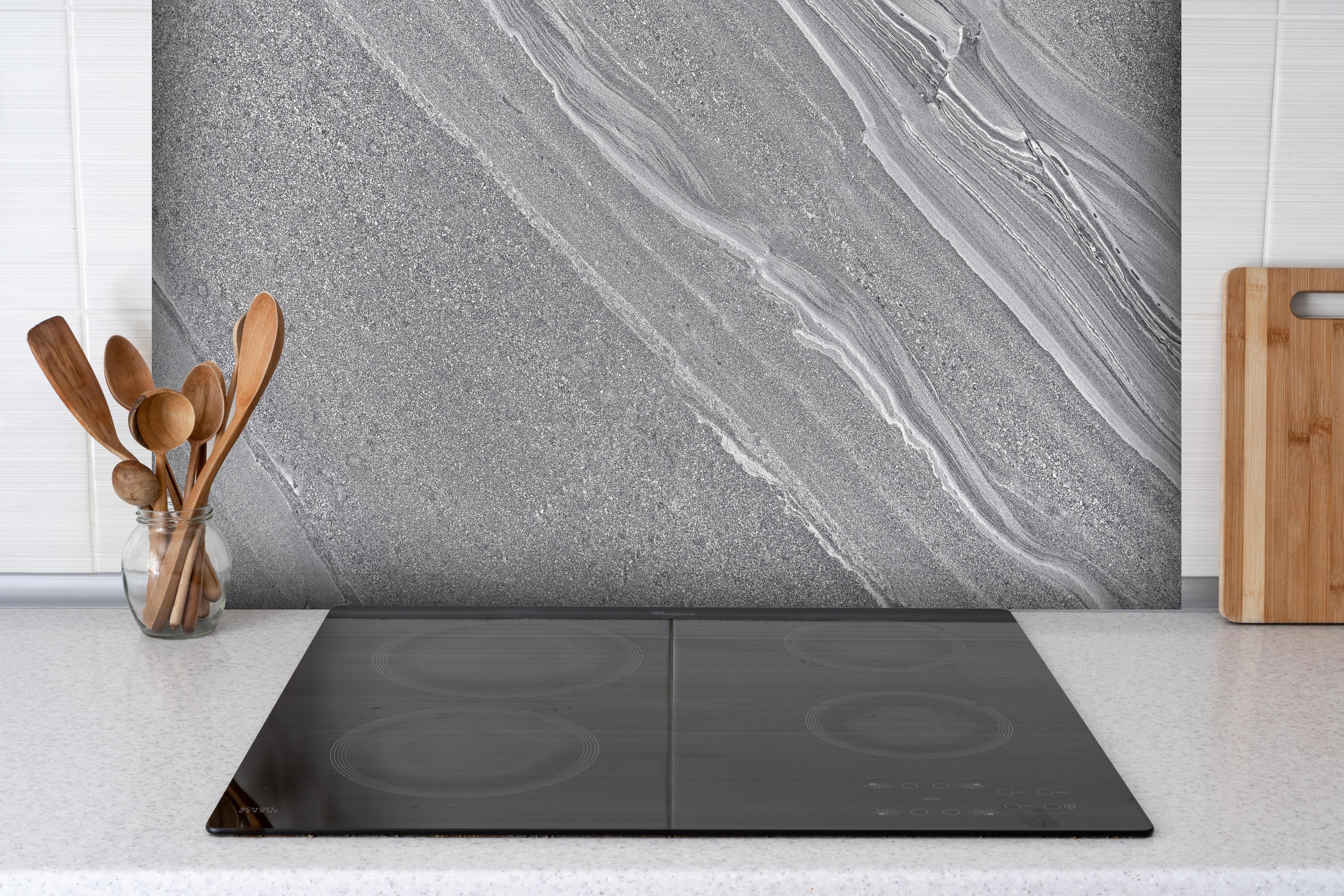 Spritzschutz - Natürlicher gräulicher Marmor hinter einem Cerankochfeld zwischen Holz-Kochutensilien