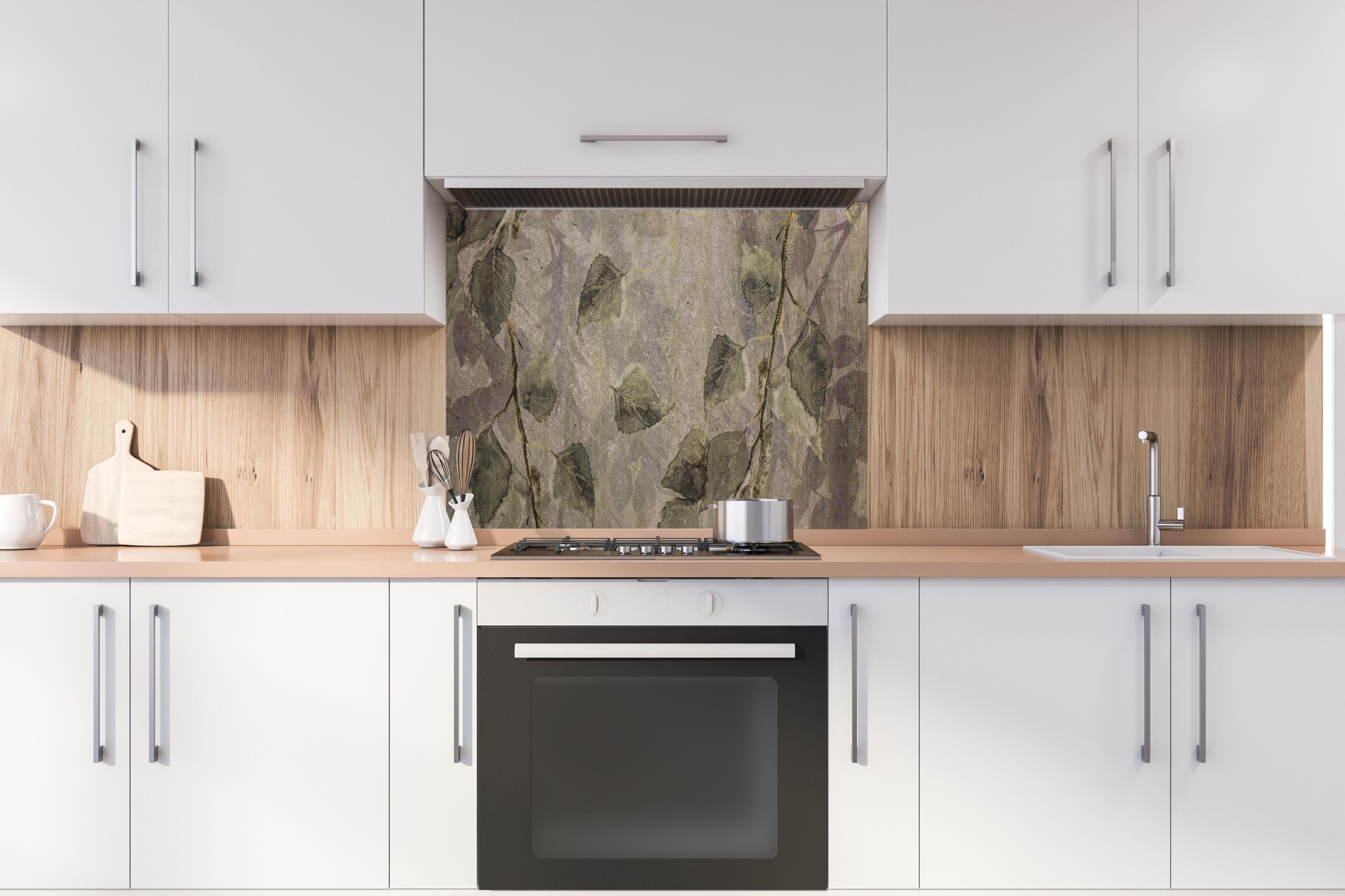 Spritzschutz - Natürliches Blattmuster auf grauen Fliesen hinter einem Cerankochfeld zwischen Holz-Kochutensilien