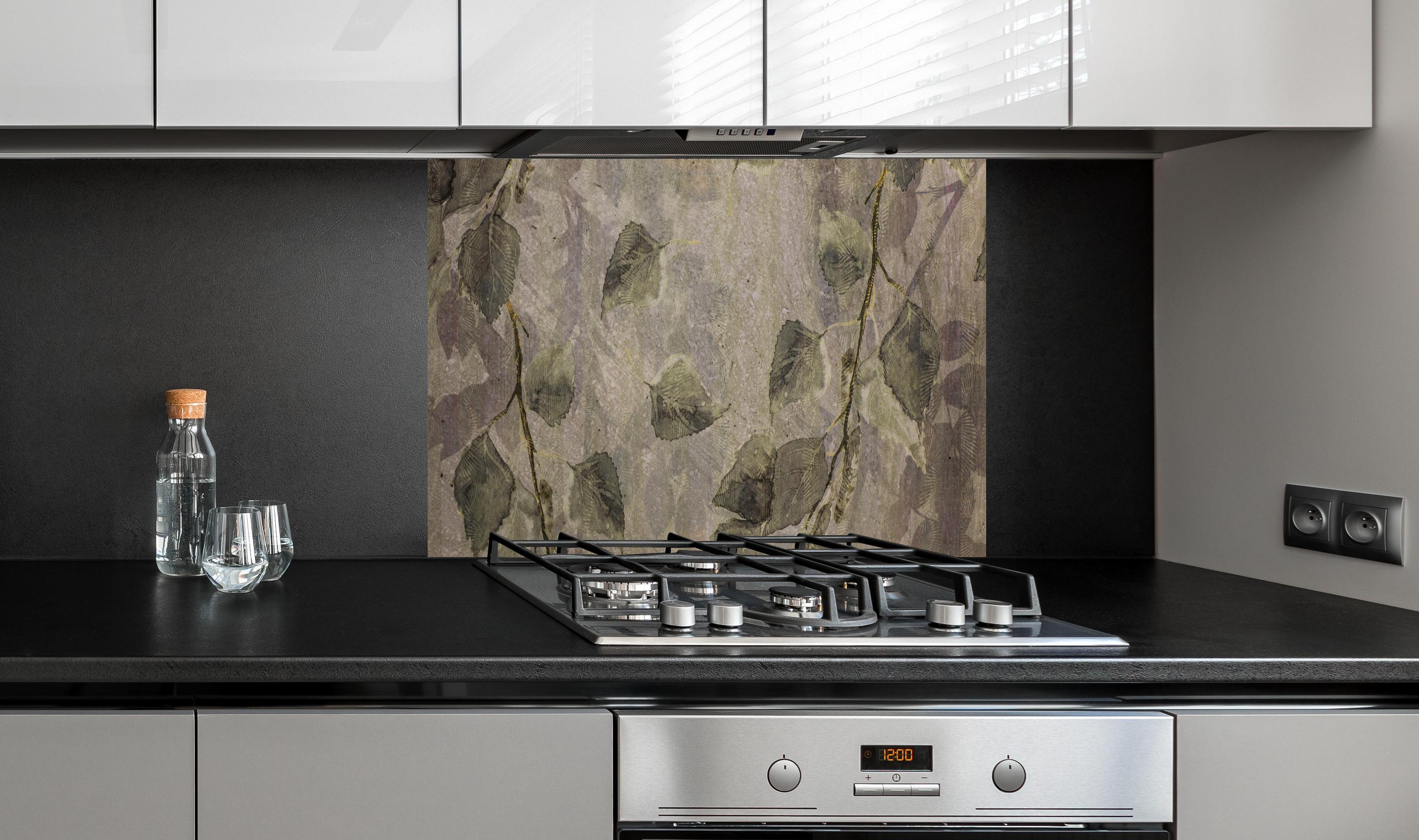 Spritzschutz - Natürliches Blattmuster auf grauen Fliesen hinter einem Cerankochfeld zwischen Holz-Kochutensilien