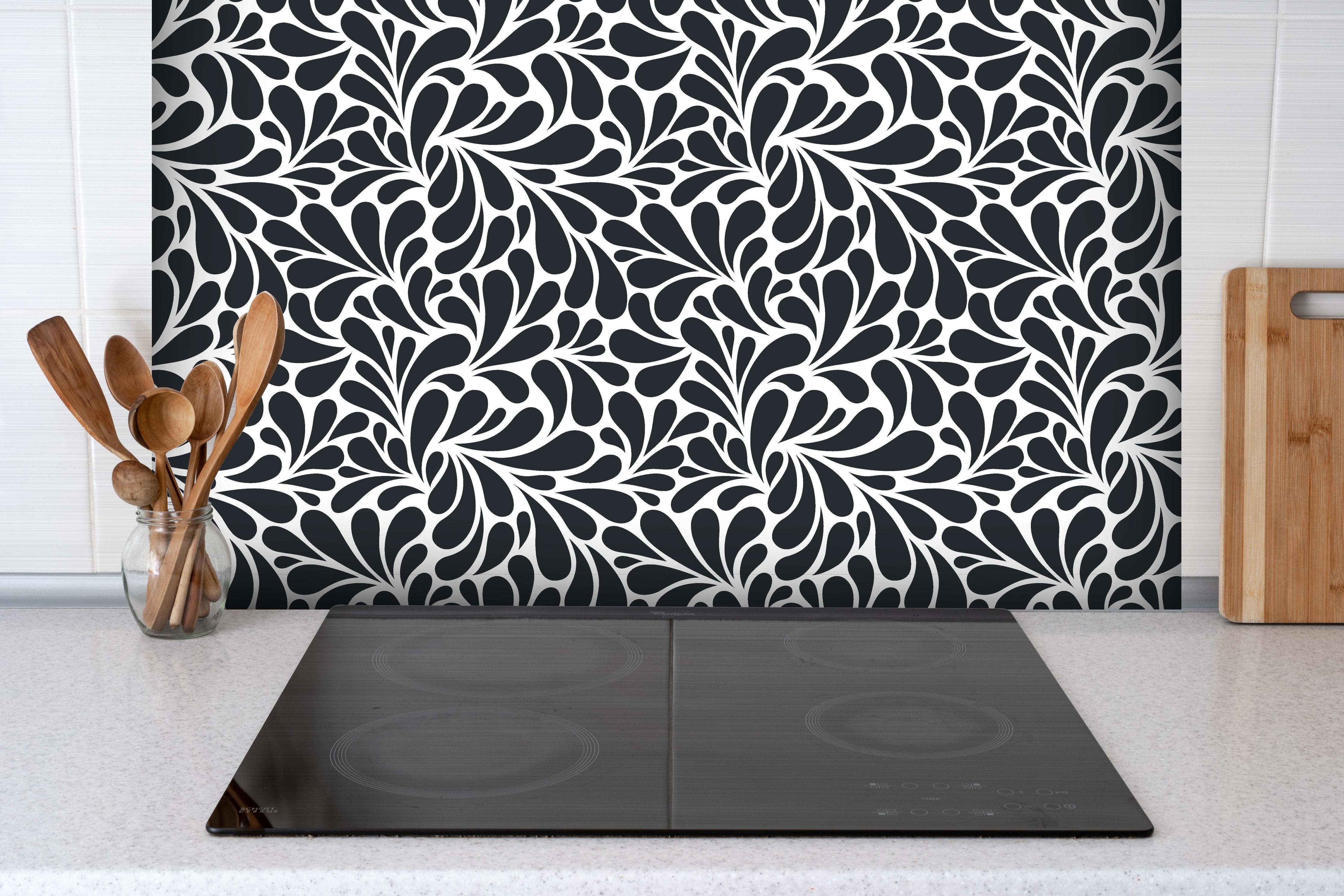 Spritzschutz - Natura Petaloso Carbone hinter einem Cerankochfeld zwischen Holz-Kochutensilien