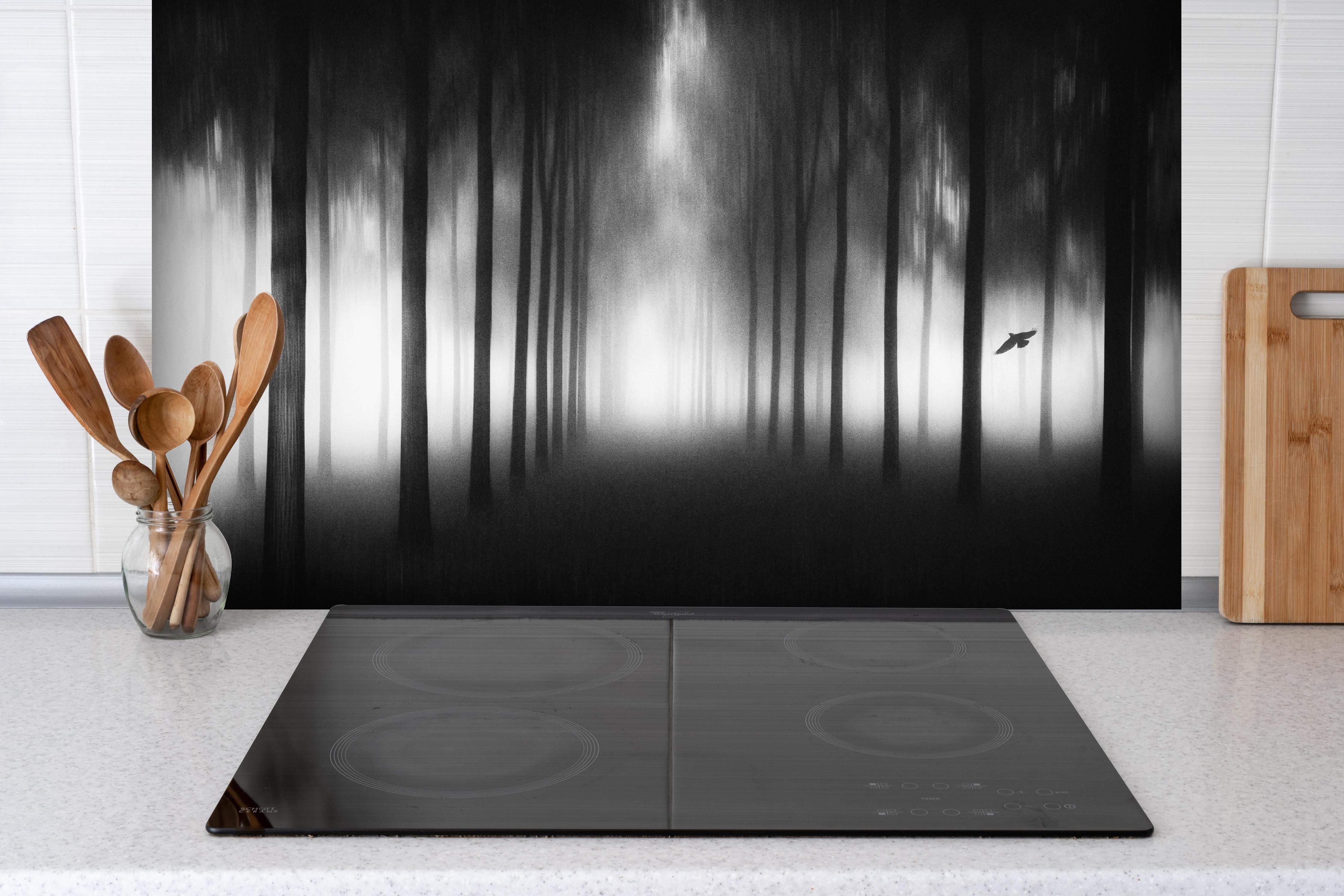 Spritzschutz - Nebeliger, dunkler Wald hinter einem Cerankochfeld zwischen Holz-Kochutensilien