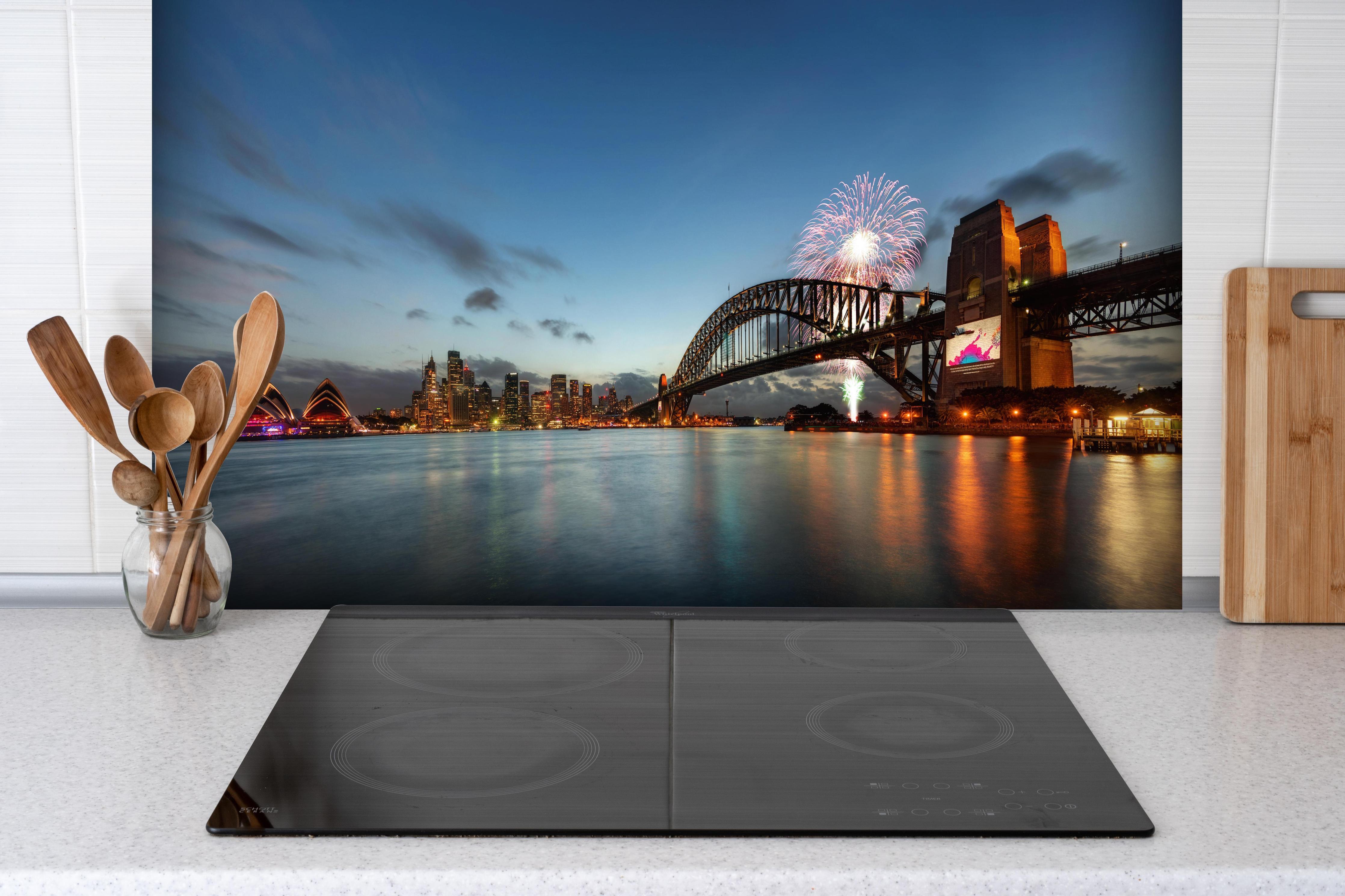 Spritzschutz - Neujahrsfeuerwerk hinter einem Cerankochfeld zwischen Holz-Kochutensilien