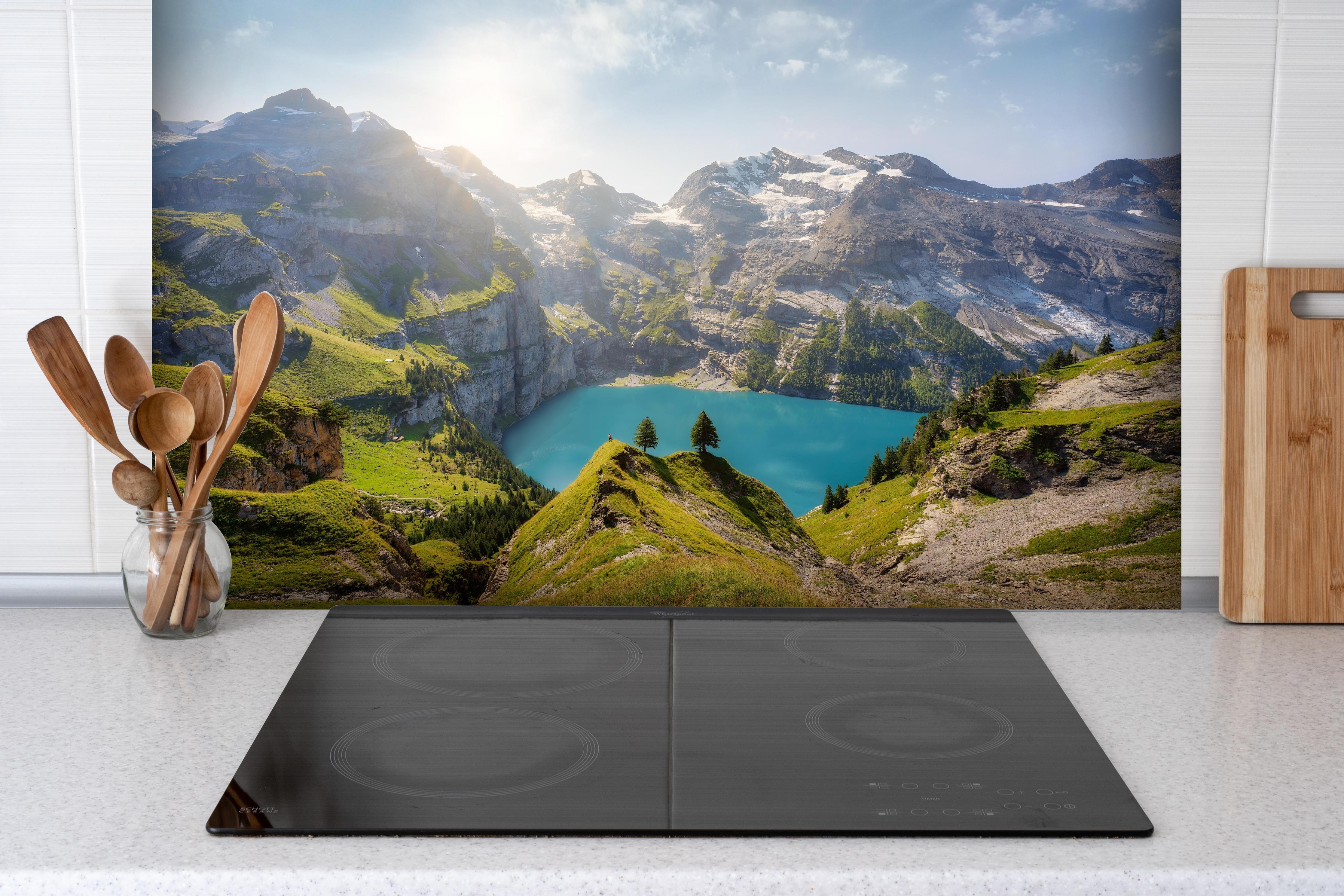 Spritzschutz - Oeschinensee in den Schweizer Alpen hinter einem Cerankochfeld zwischen Holz-Kochutensilien