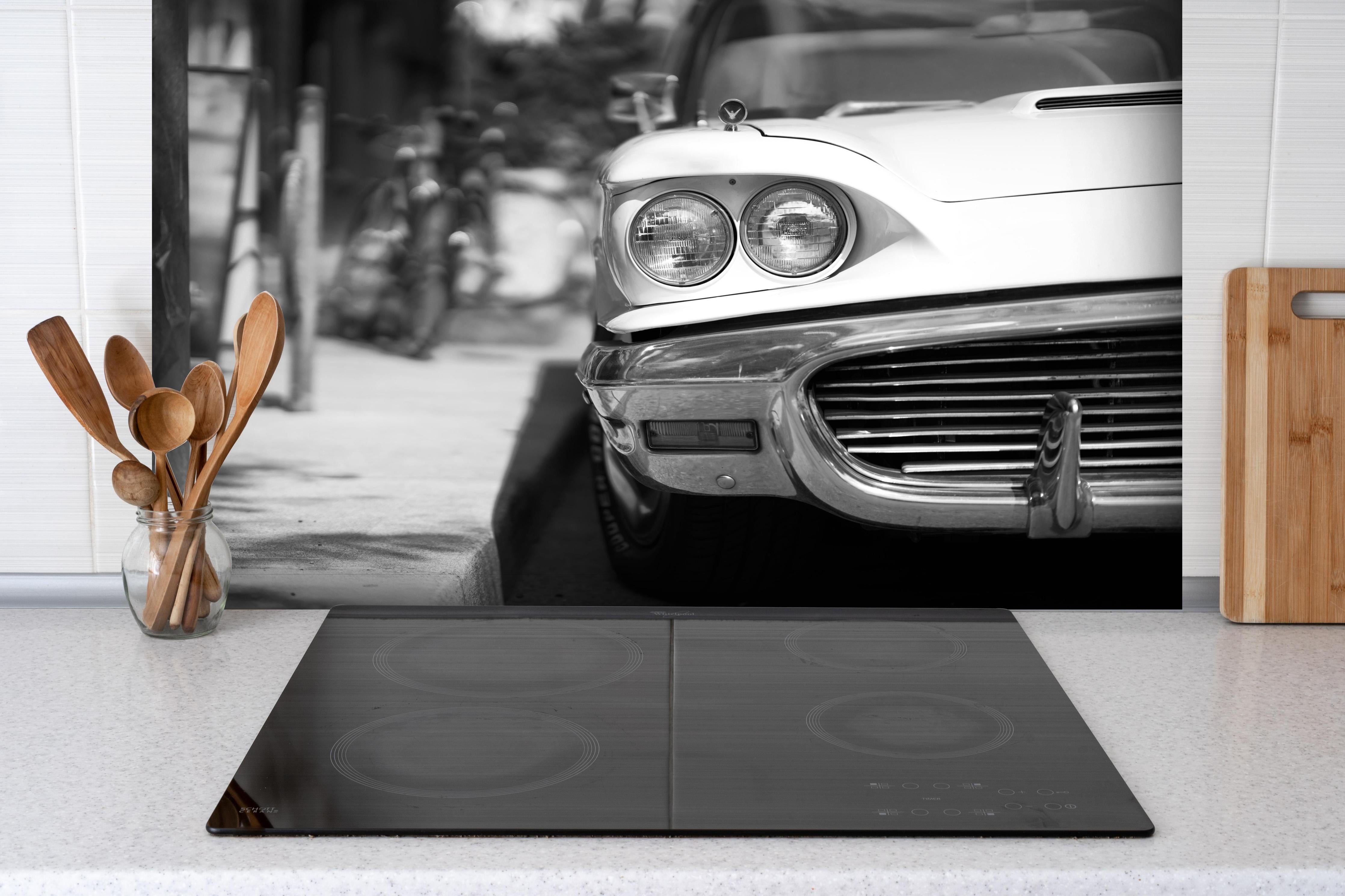 Spritzschutz - Oldtimer-Scheinwerfer hinter einem Cerankochfeld zwischen Holz-Kochutensilien