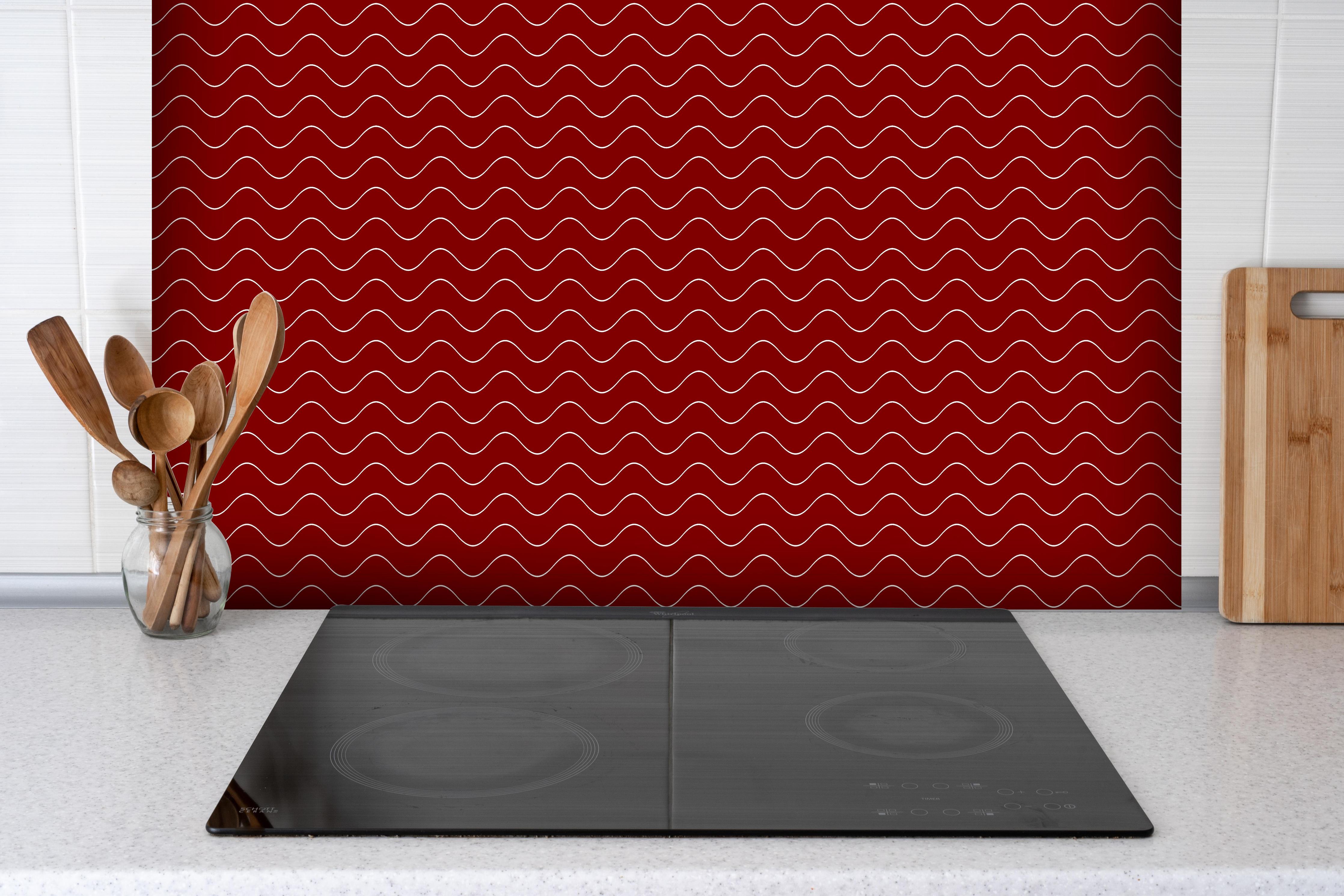 Spritzschutz - Onde Abisso Granata hinter einem Cerankochfeld zwischen Holz-Kochutensilien
