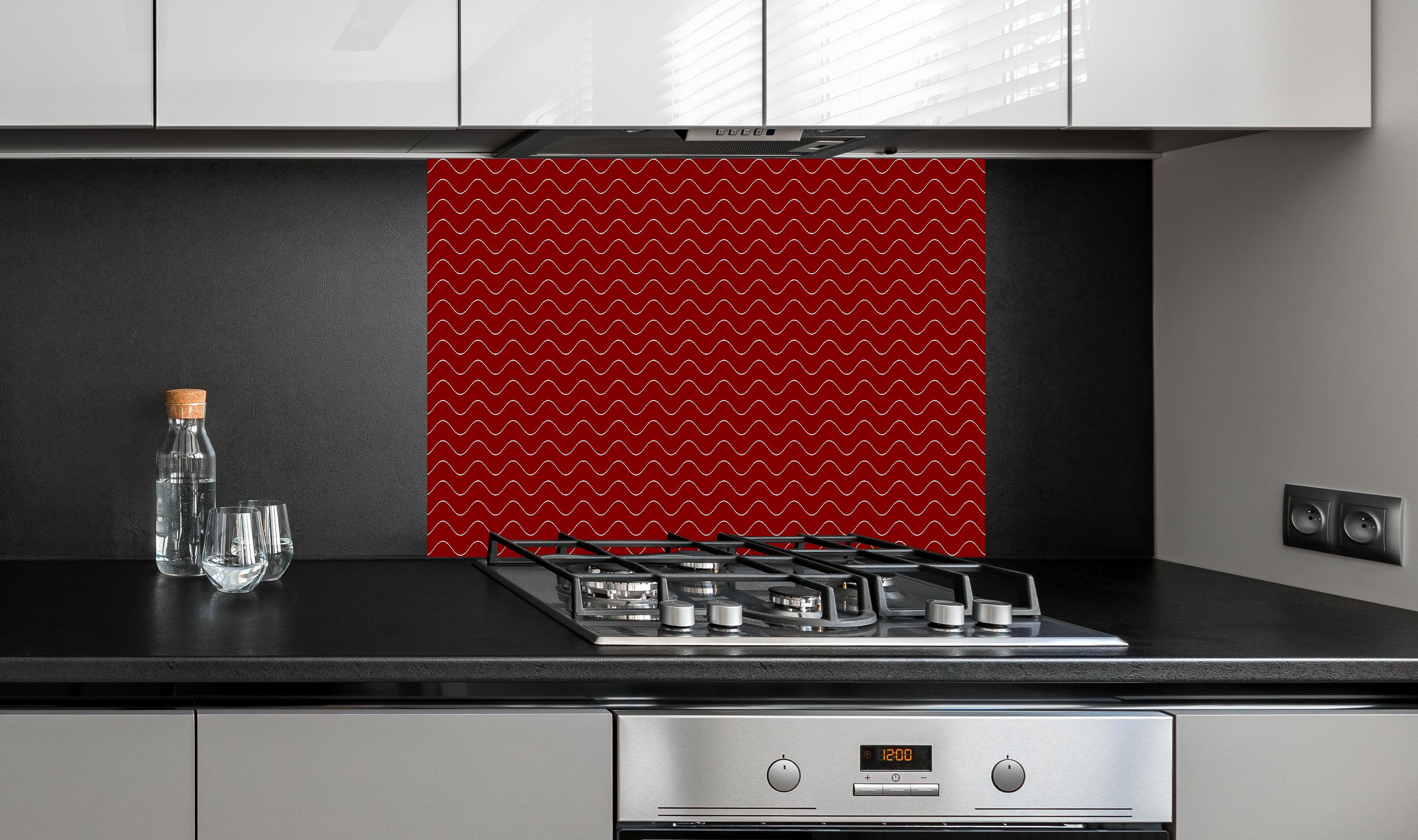 Spritzschutz - Onde Abisso Granata hinter einem Cerankochfeld zwischen Holz-Kochutensilien