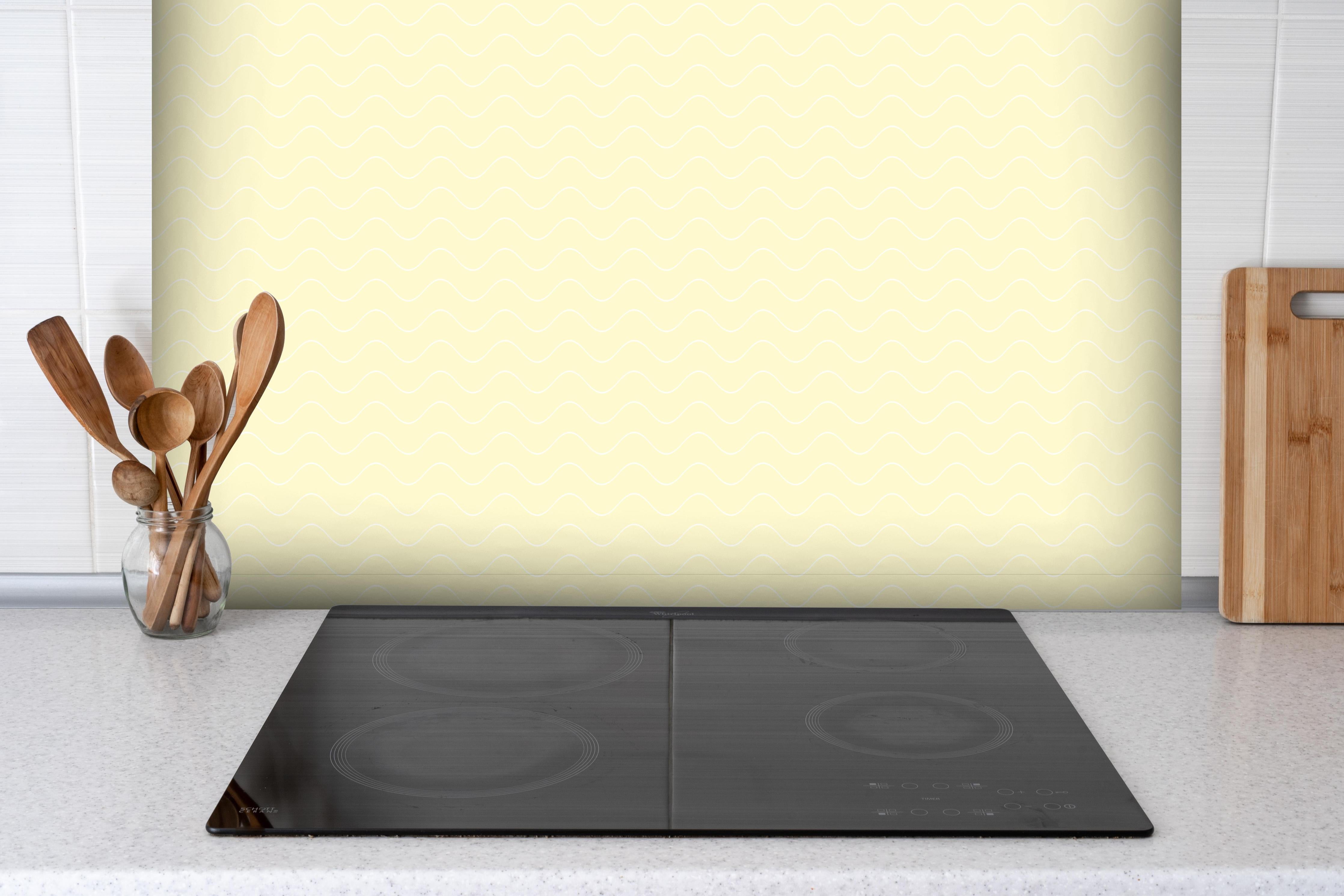 Spritzschutz - Onde Abisso Limone crema hinter einem Cerankochfeld zwischen Holz-Kochutensilien