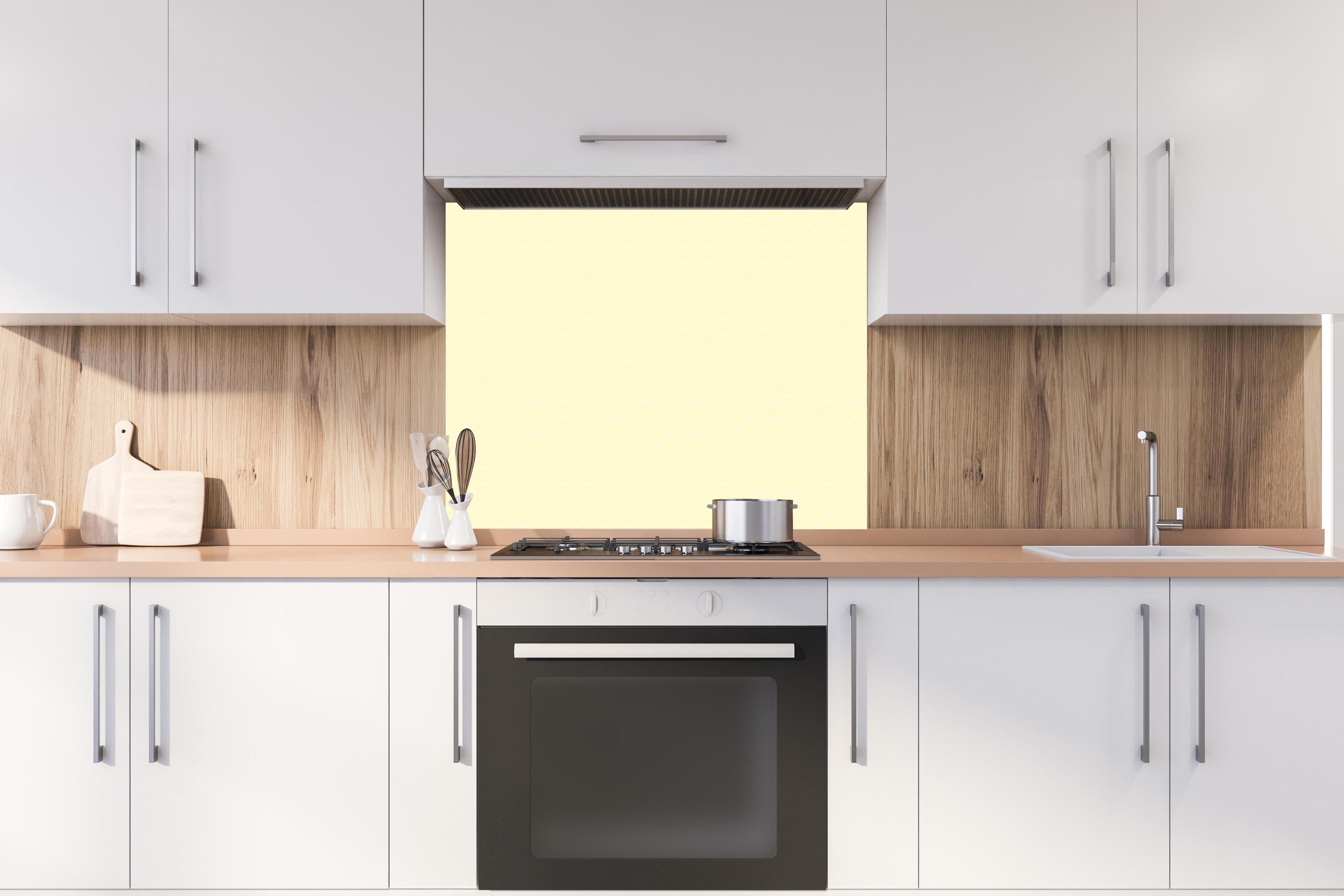 Spritzschutz - Onde Abisso Limone crema hinter einem Cerankochfeld zwischen Holz-Kochutensilien