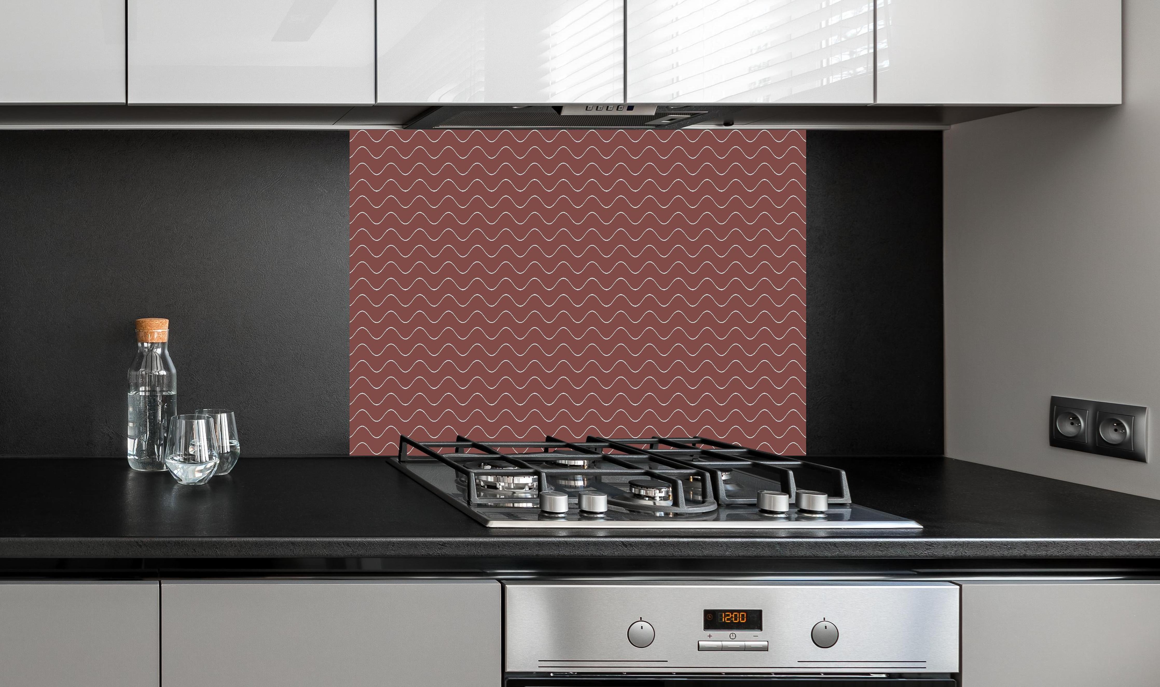 Spritzschutz - Onde Abisso Mattone hinter einem Cerankochfeld zwischen Holz-Kochutensilien