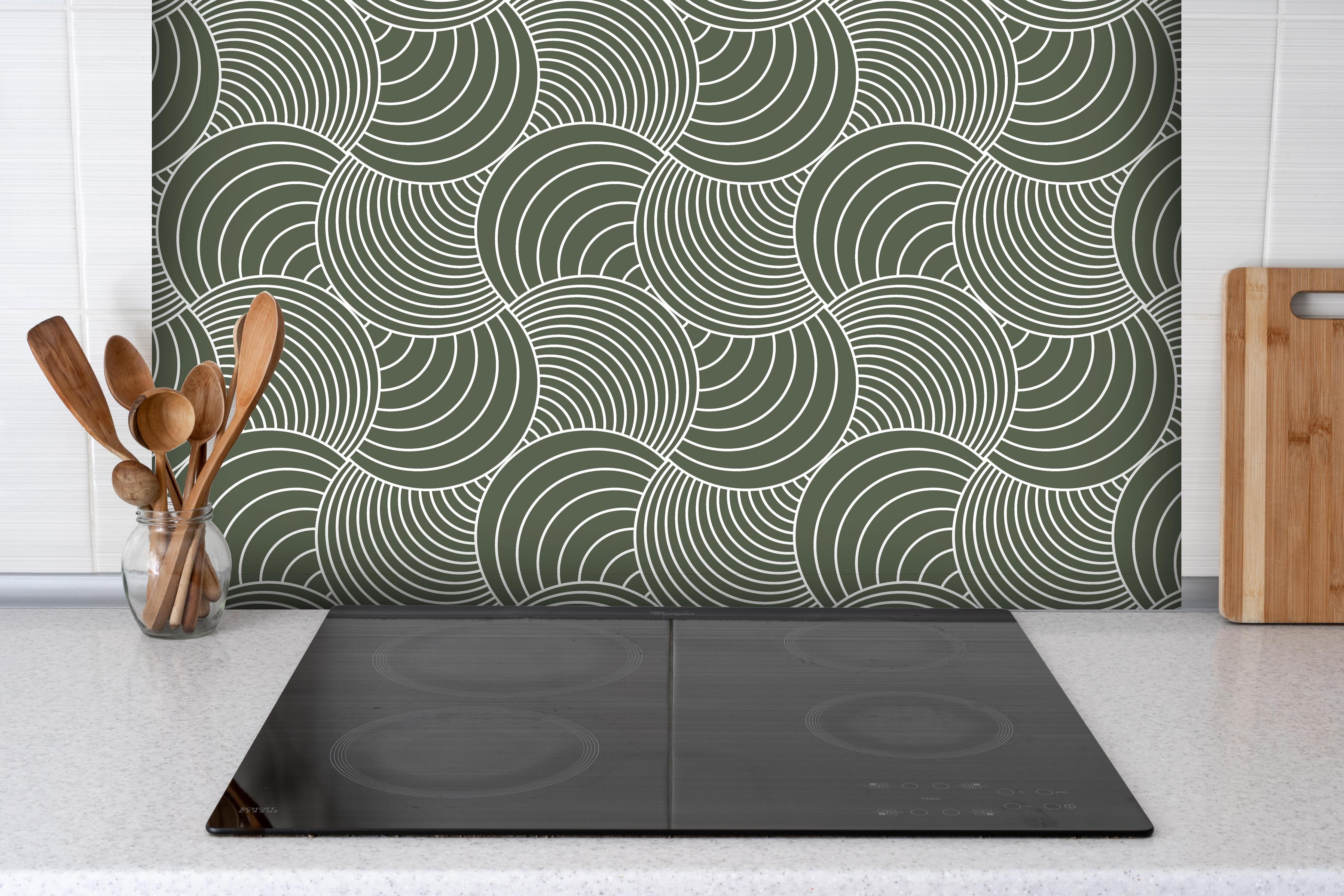 Spritzschutz - Onde Imaginario Bosco hinter einem Cerankochfeld zwischen Holz-Kochutensilien