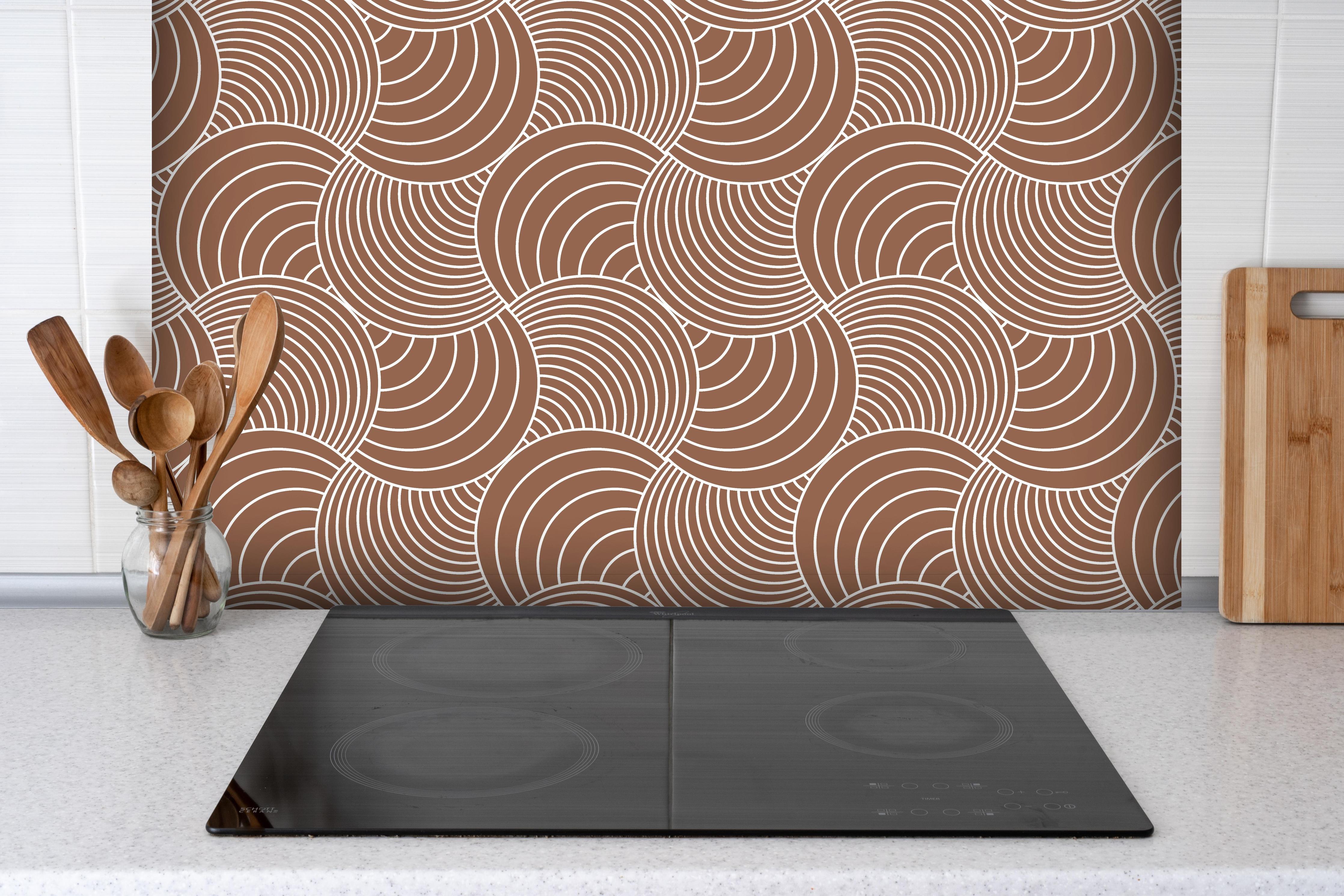 Spritzschutz - Onde Imaginario Cannella hinter einem Cerankochfeld zwischen Holz-Kochutensilien