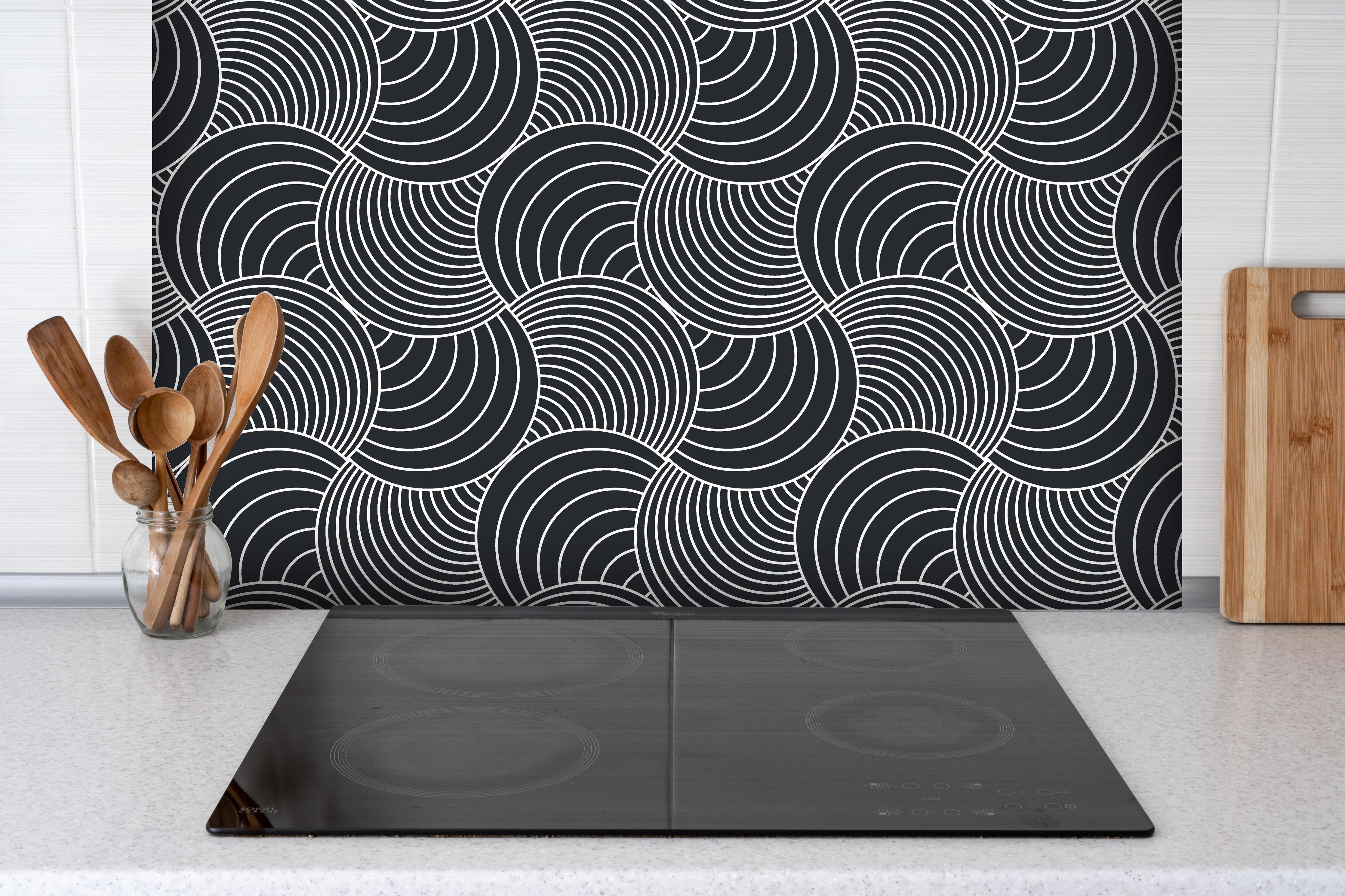 Spritzschutz - Onde Imaginario Carbone hinter einem Cerankochfeld zwischen Holz-Kochutensilien