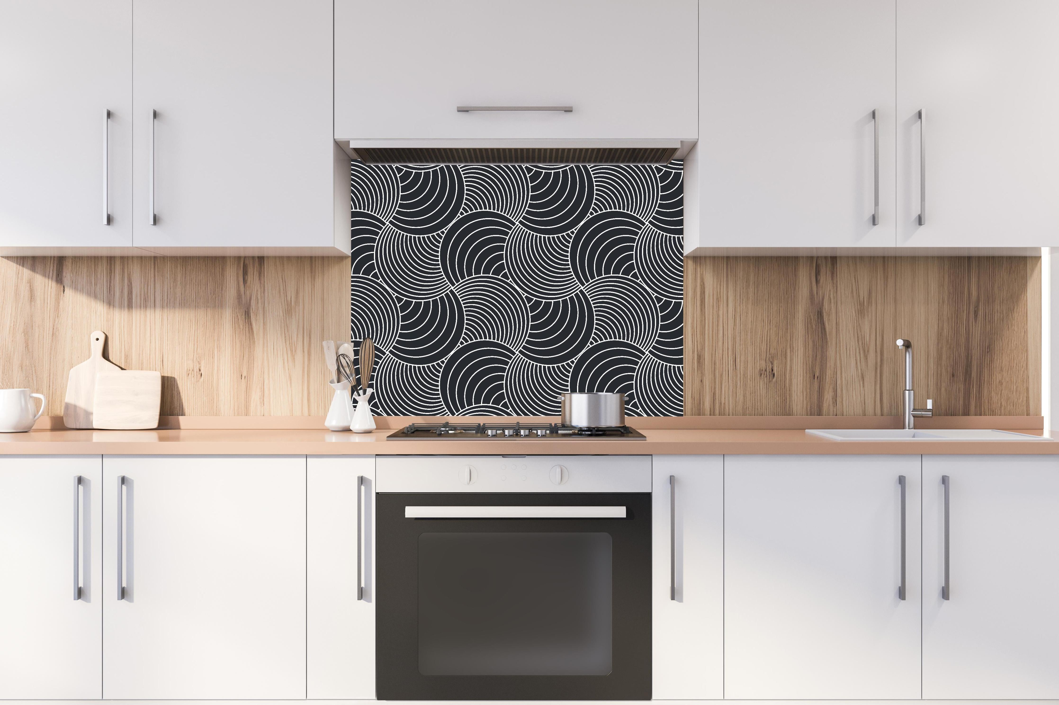 Spritzschutz - Onde Imaginario Carbone hinter einem Cerankochfeld zwischen Holz-Kochutensilien