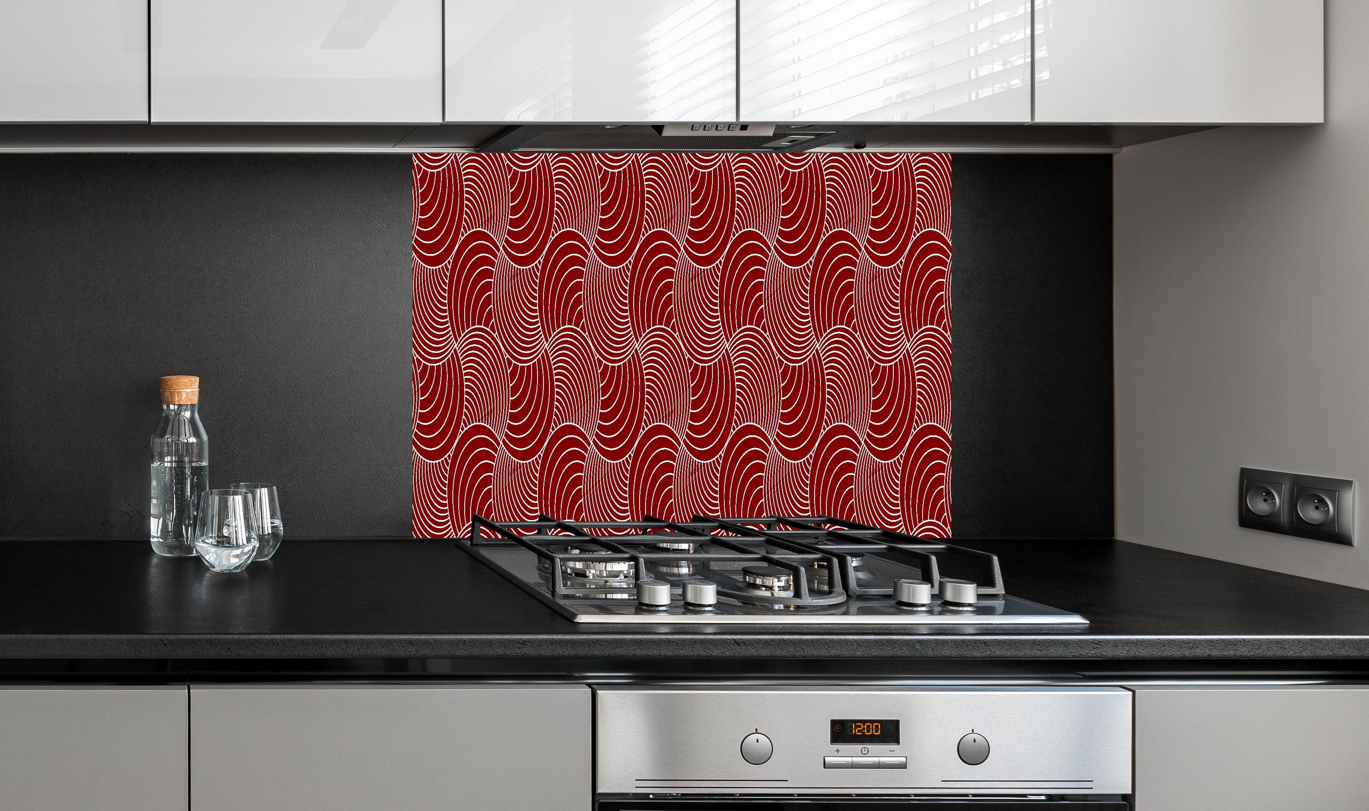 Spritzschutz - Onde Imaginario Granata hinter einem Cerankochfeld zwischen Holz-Kochutensilien
