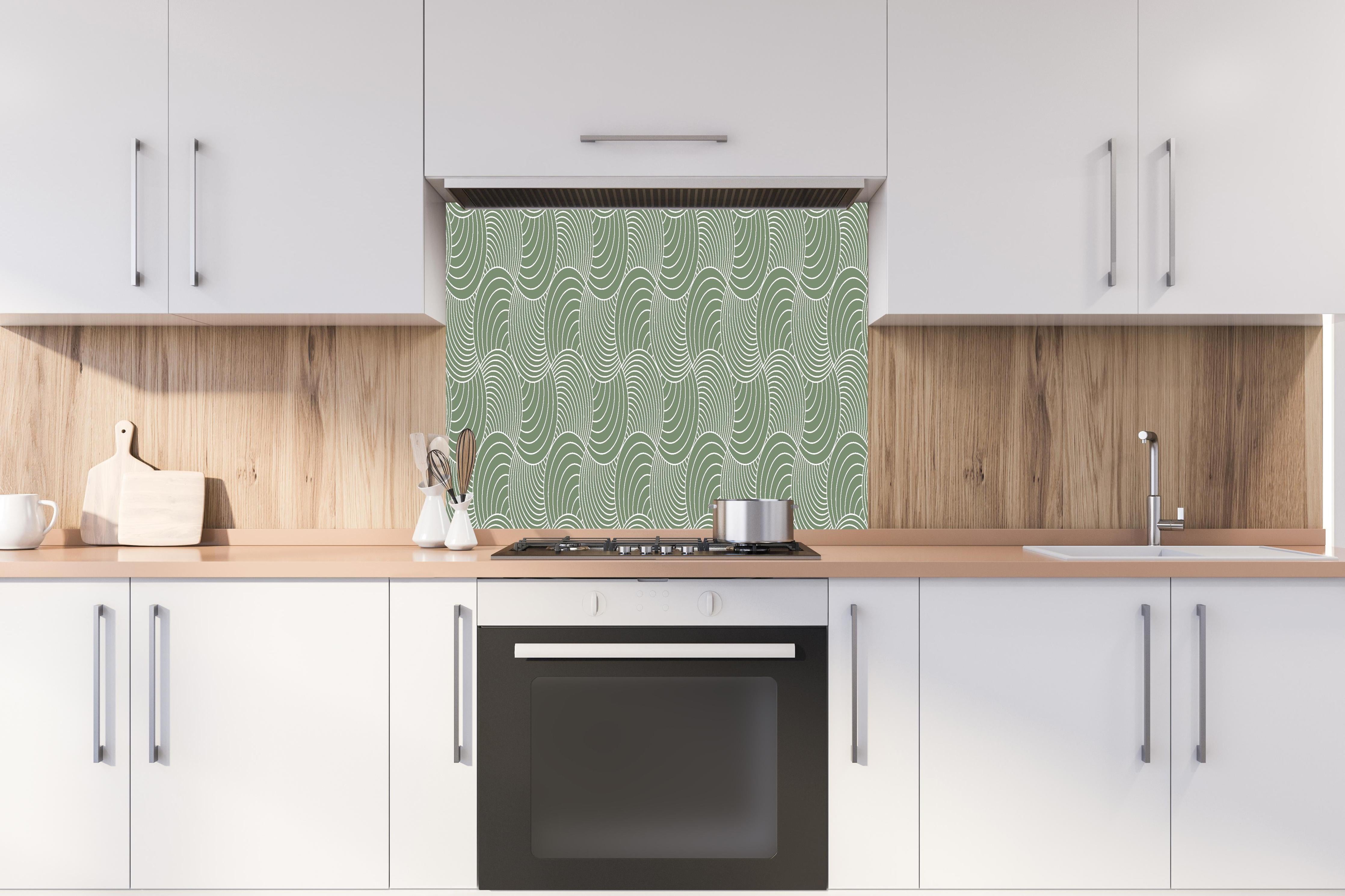 Spritzschutz - Onde Imaginario Oliva hinter einem Cerankochfeld zwischen Holz-Kochutensilien