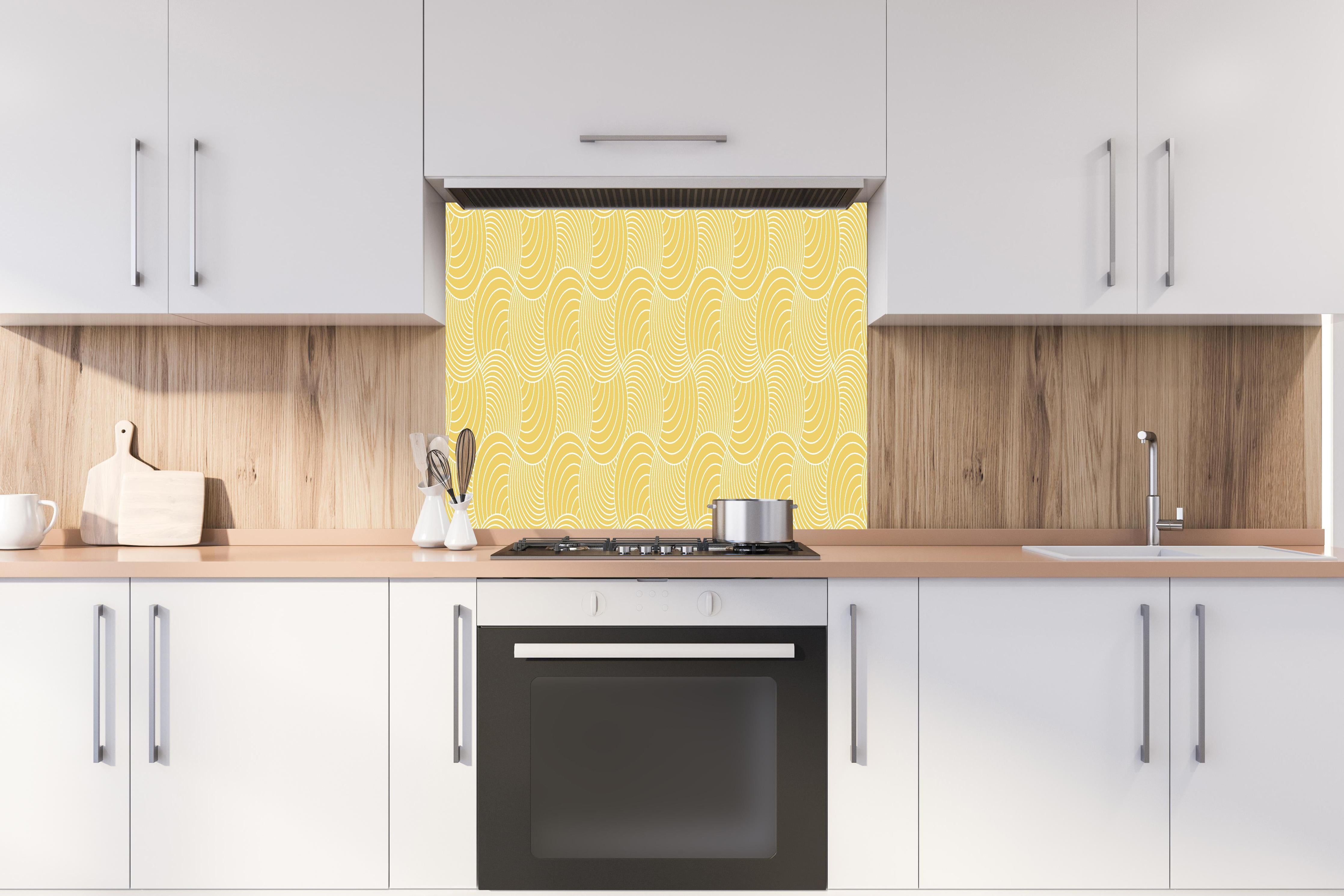 Spritzschutz - Onde Imaginario Oro hinter einem Cerankochfeld zwischen Holz-Kochutensilien