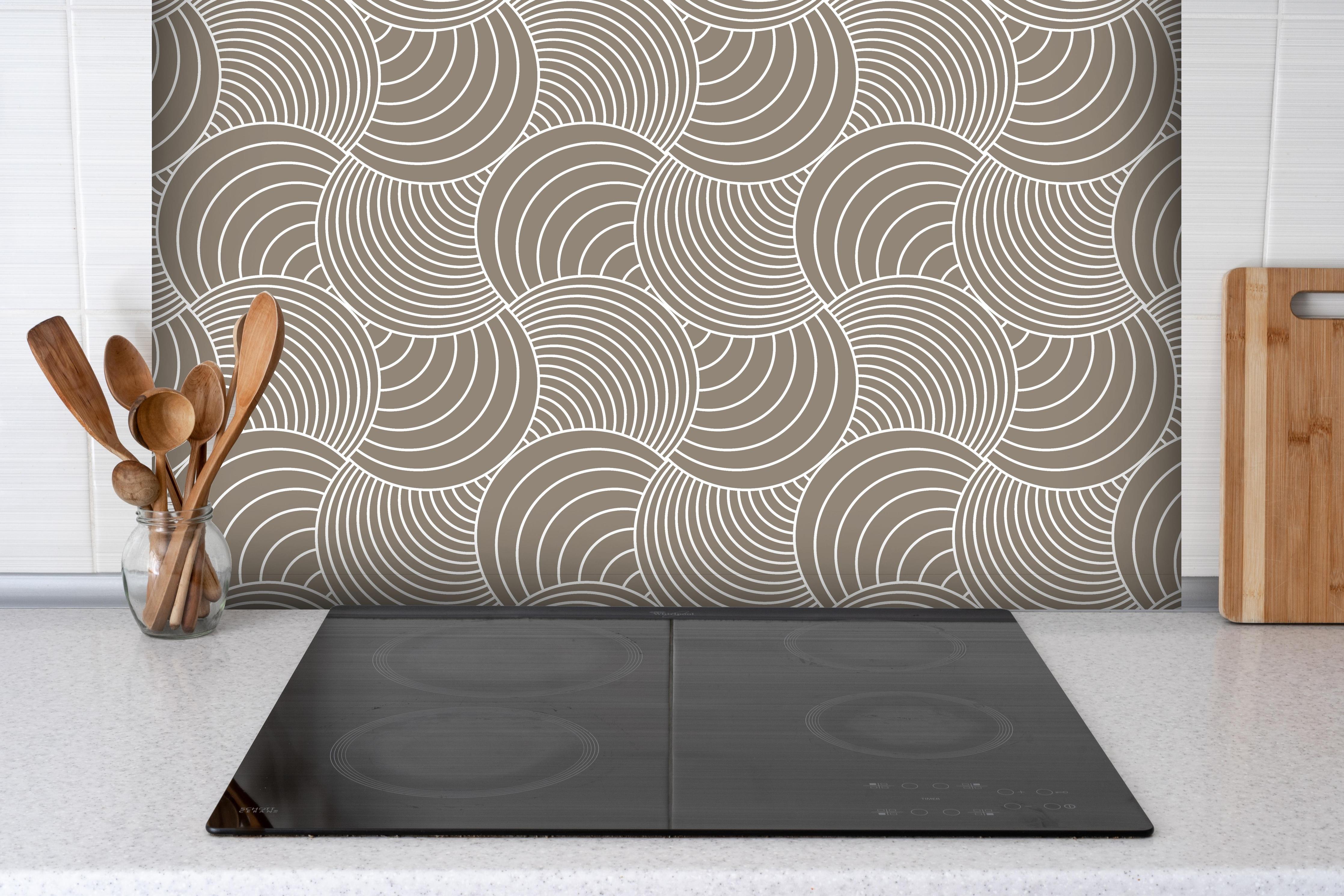 Spritzschutz - Onde Imaginario Tortora hinter einem Cerankochfeld zwischen Holz-Kochutensilien