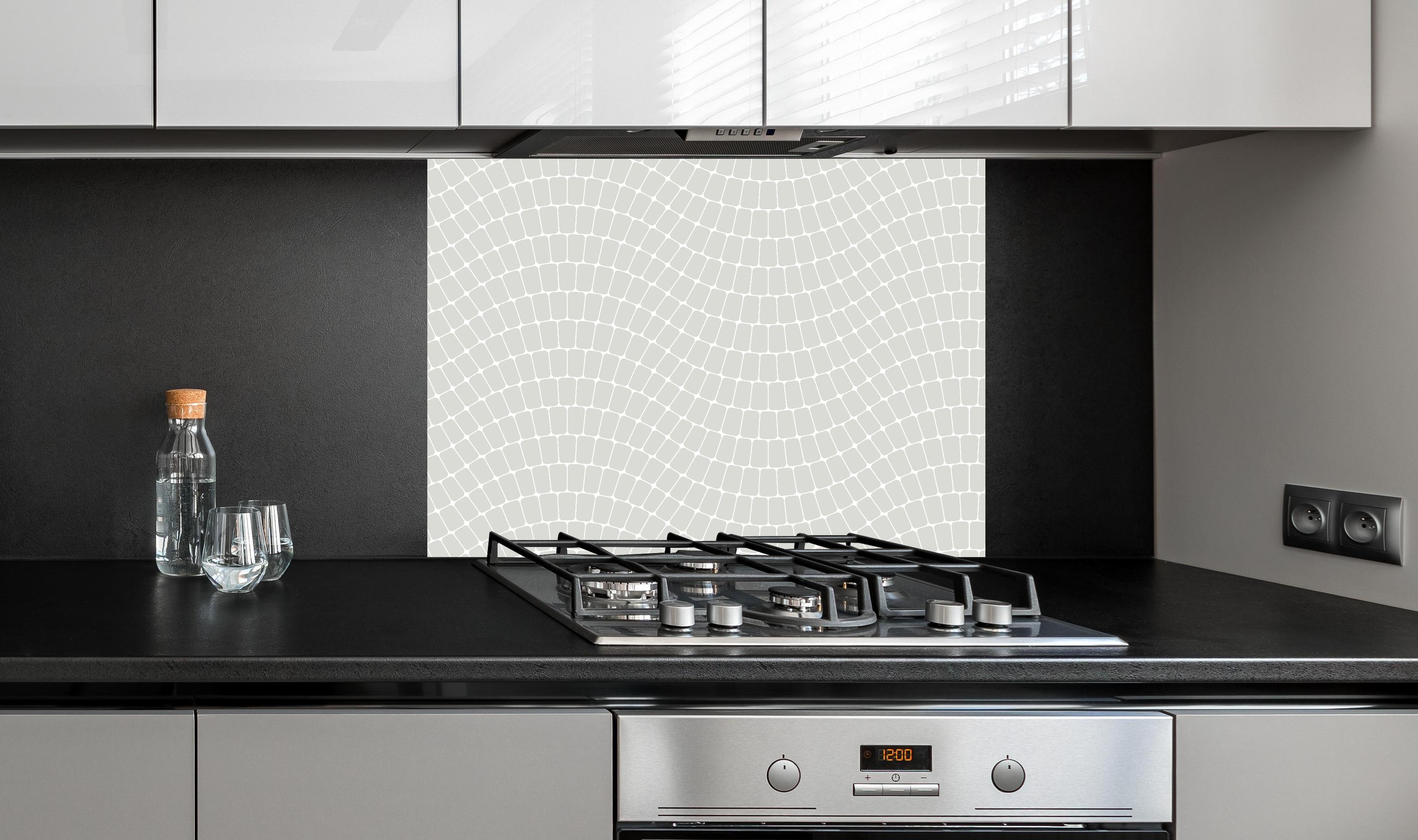 Spritzschutz - Onde Sinuoso Argento hinter einem Cerankochfeld zwischen Holz-Kochutensilien