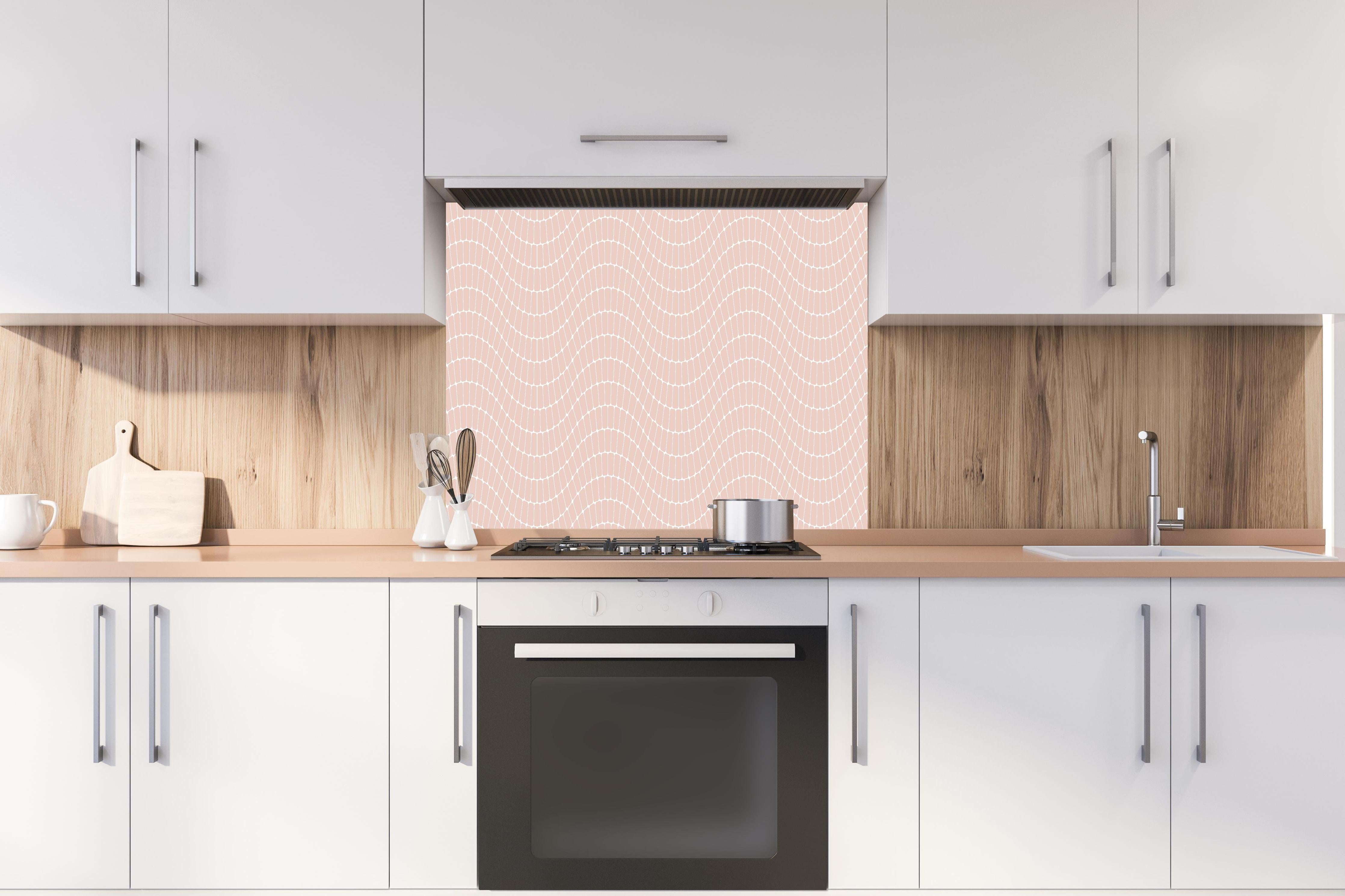 Spritzschutz - Onde Sinuoso Cipria hinter einem Cerankochfeld zwischen Holz-Kochutensilien