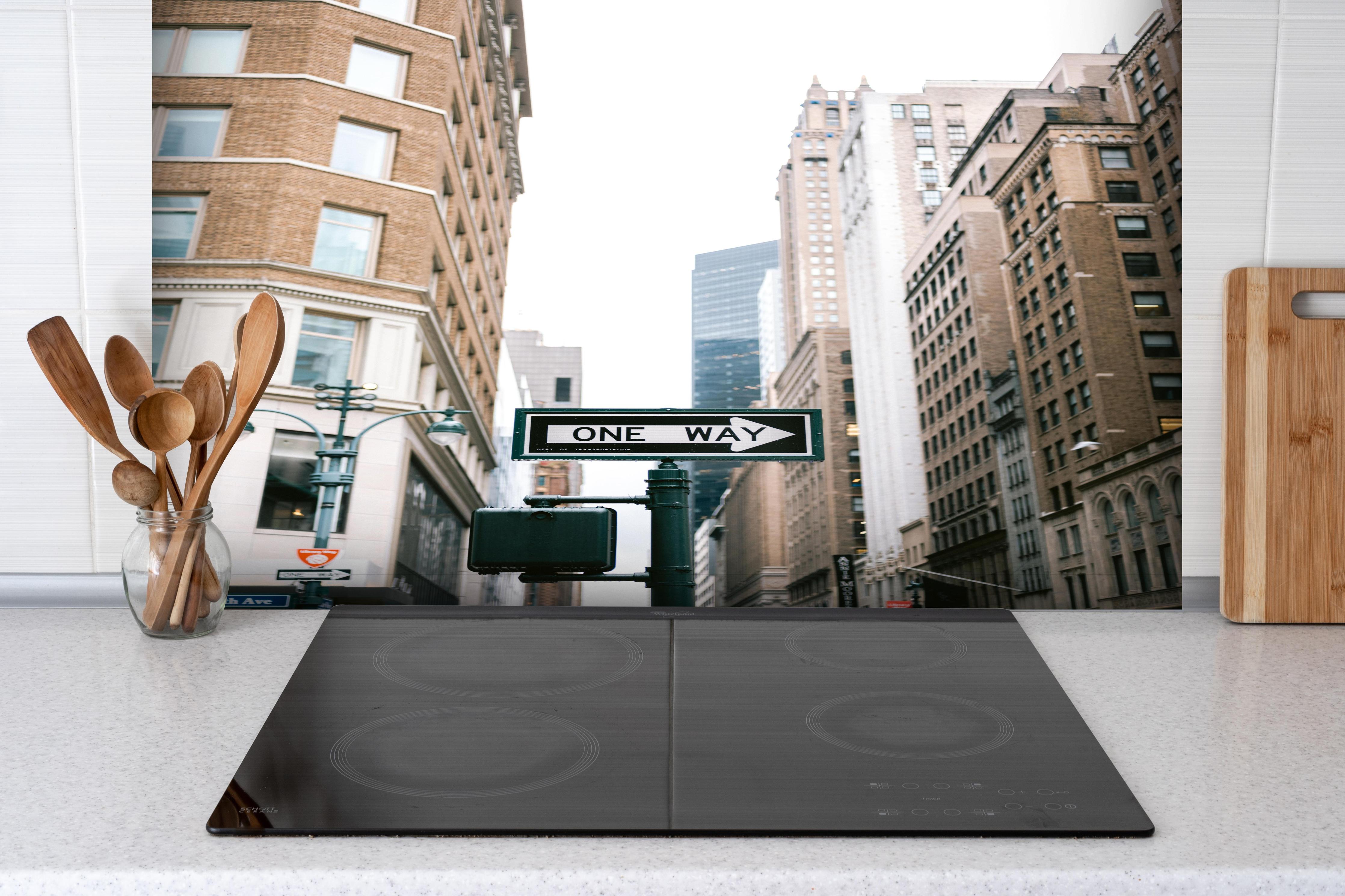 Spritzschutz - One Way Schild Fifth Avenue NYC hinter einem Cerankochfeld zwischen Holz-Kochutensilien