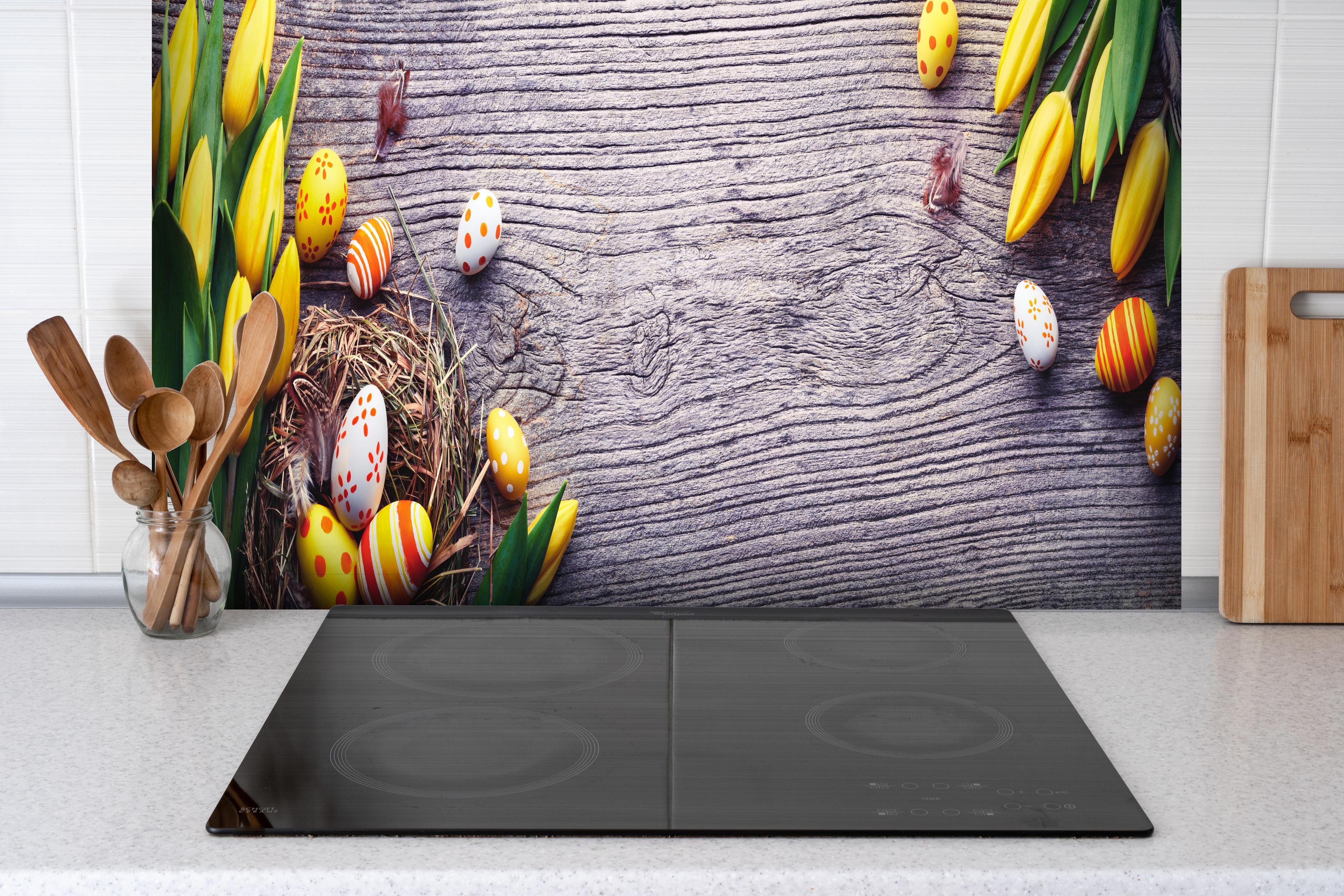 Spritzschutz - Ostereier auf Holztisch hinter einem Cerankochfeld zwischen Holz-Kochutensilien
