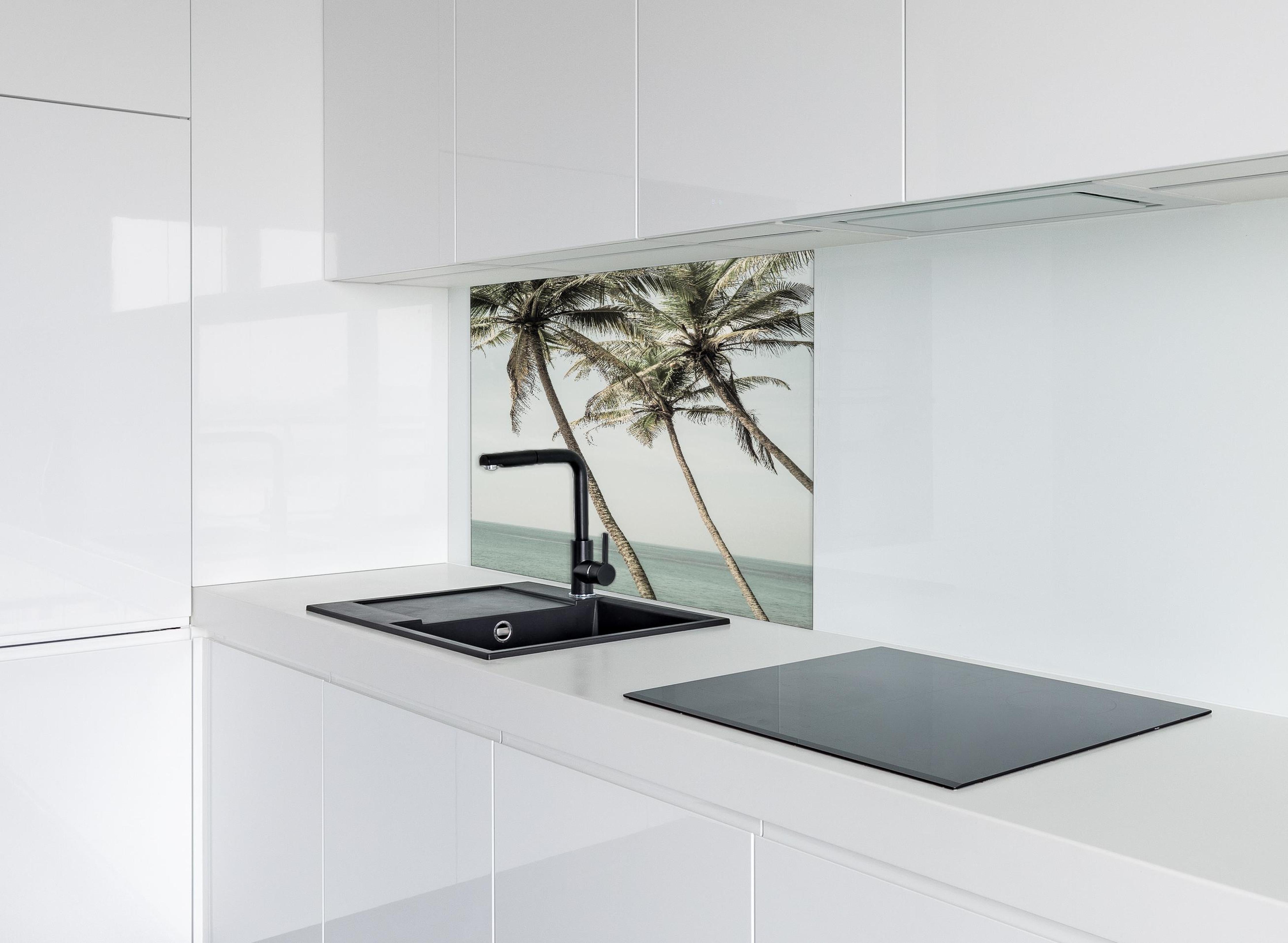 Spritzschutz - Palmen am Meer hinter einem Cerankochfeld zwischen Holz-Kochutensilien