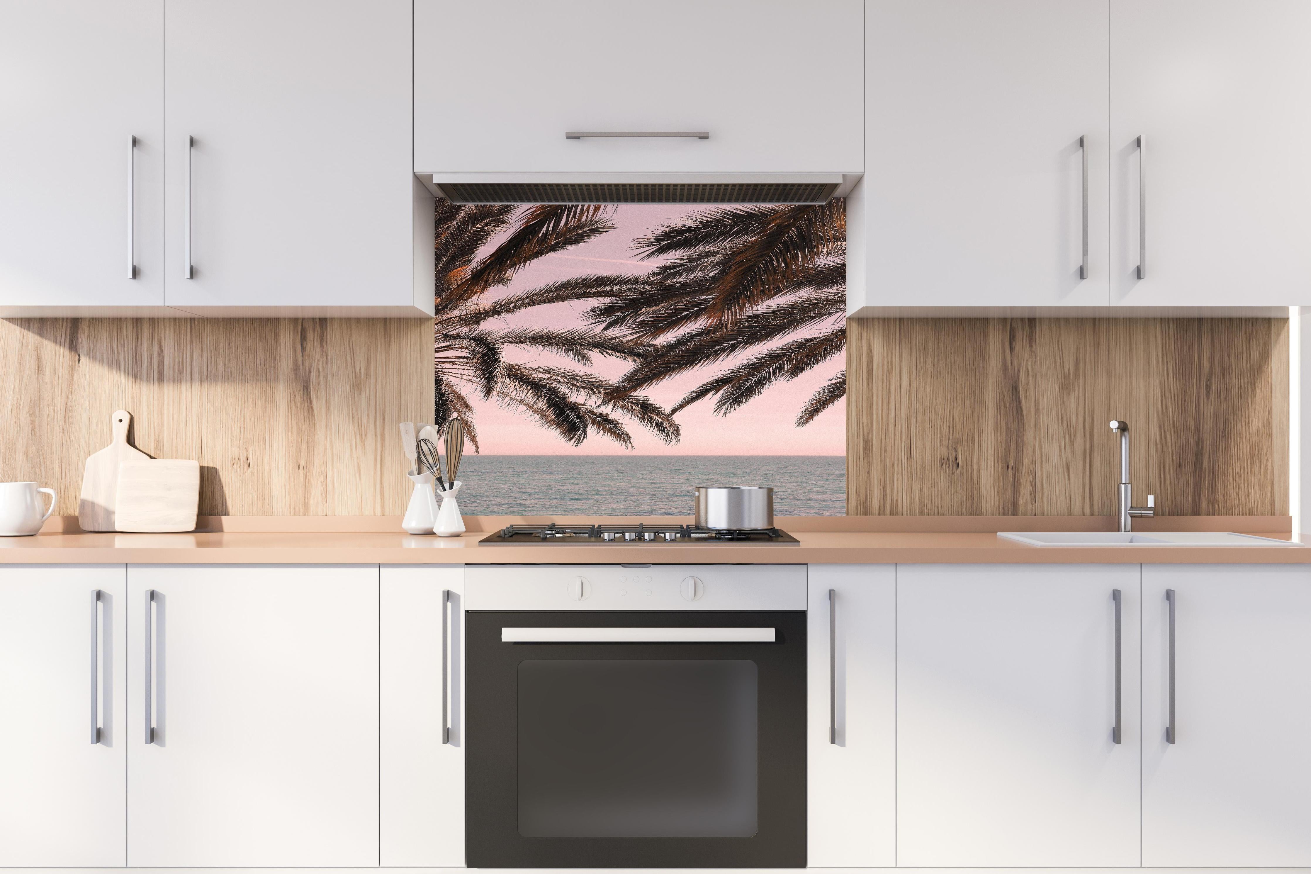 Spritzschutz - Palmen an der Küste hinter einem Cerankochfeld zwischen Holz-Kochutensilien