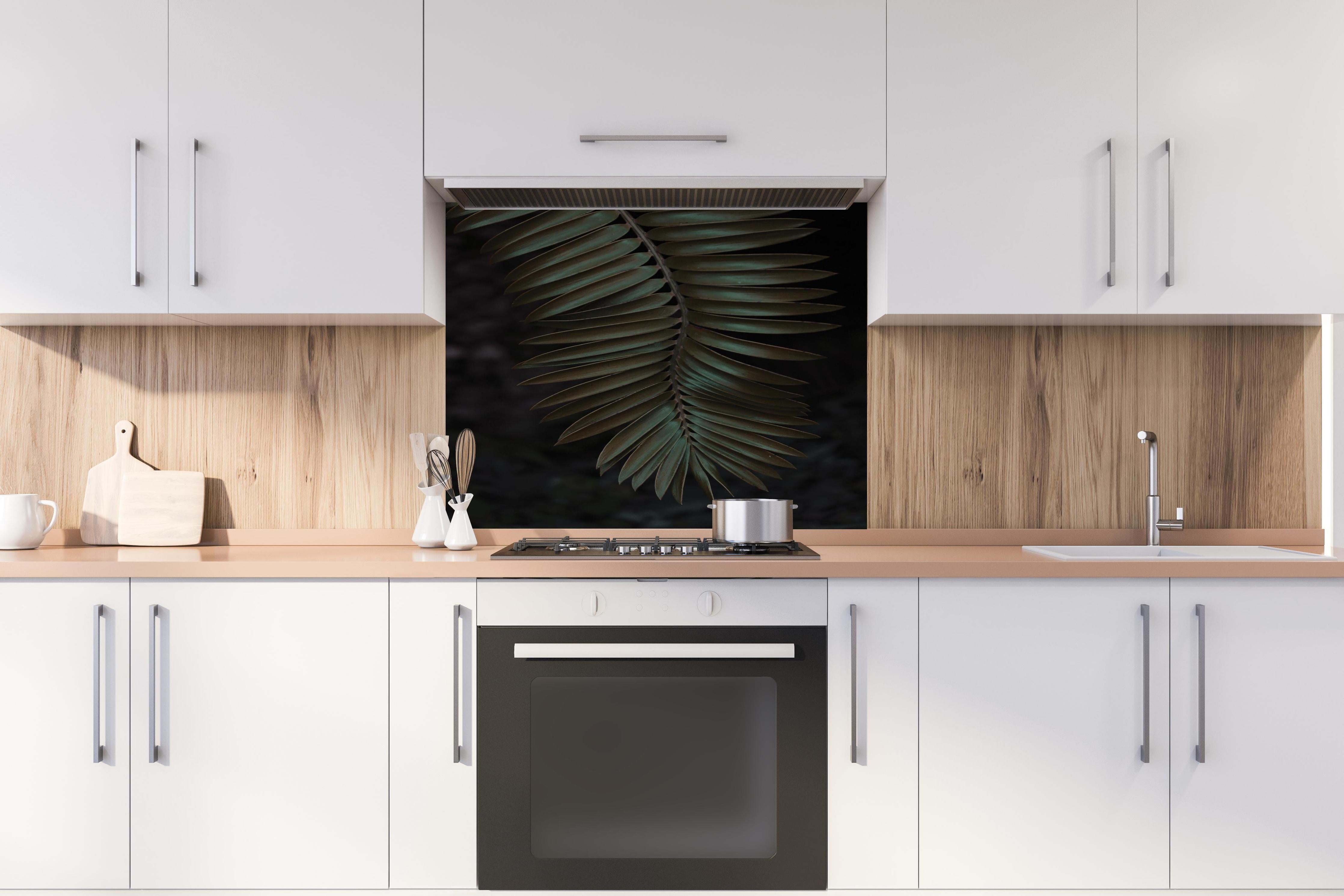 Spritzschutz - Palmenblätter hinter einem Cerankochfeld zwischen Holz-Kochutensilien