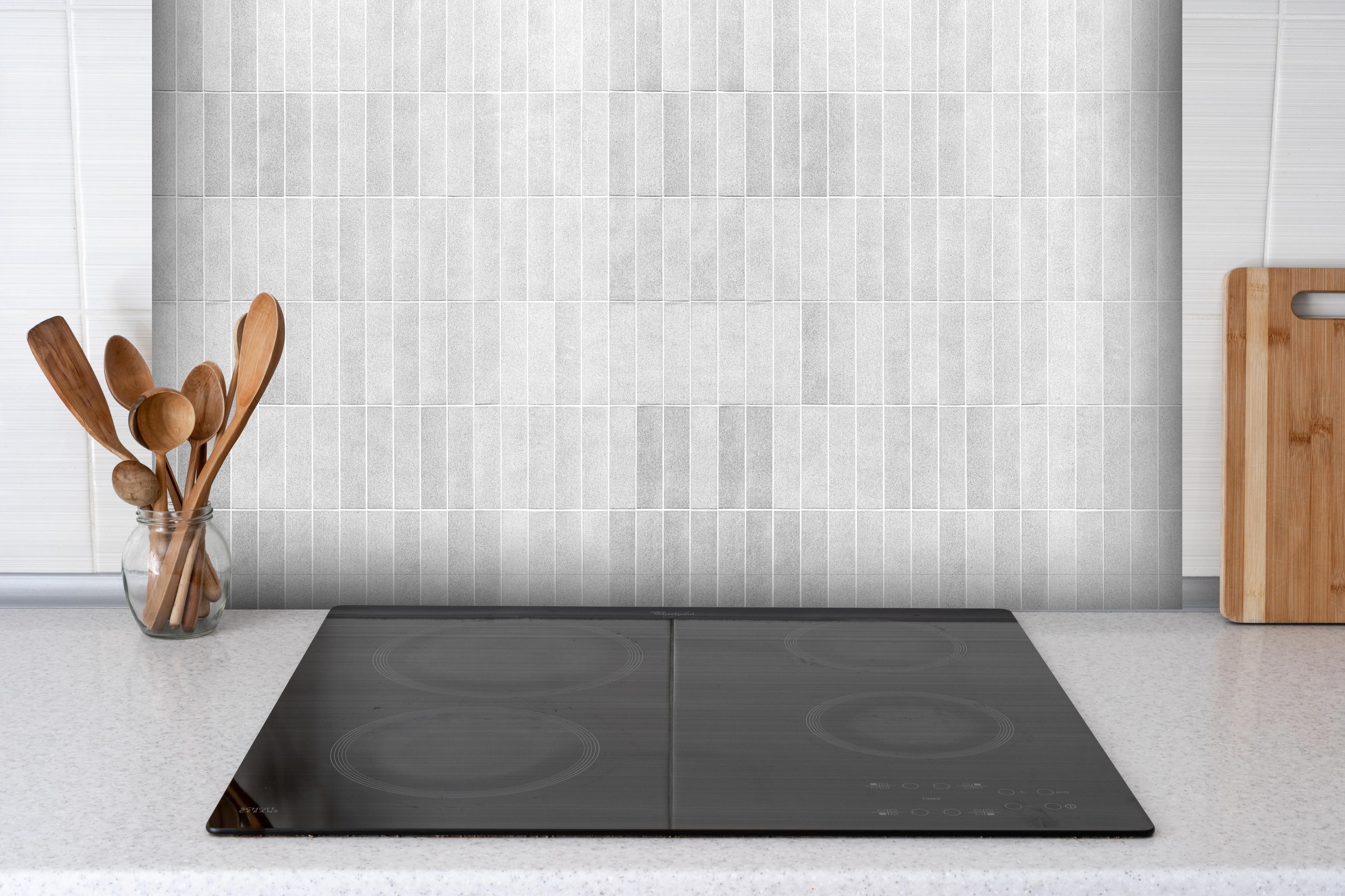 Spritzschutz - Panorama - Vintage weißen Fliesen hinter einem Cerankochfeld zwischen Holz-Kochutensilien