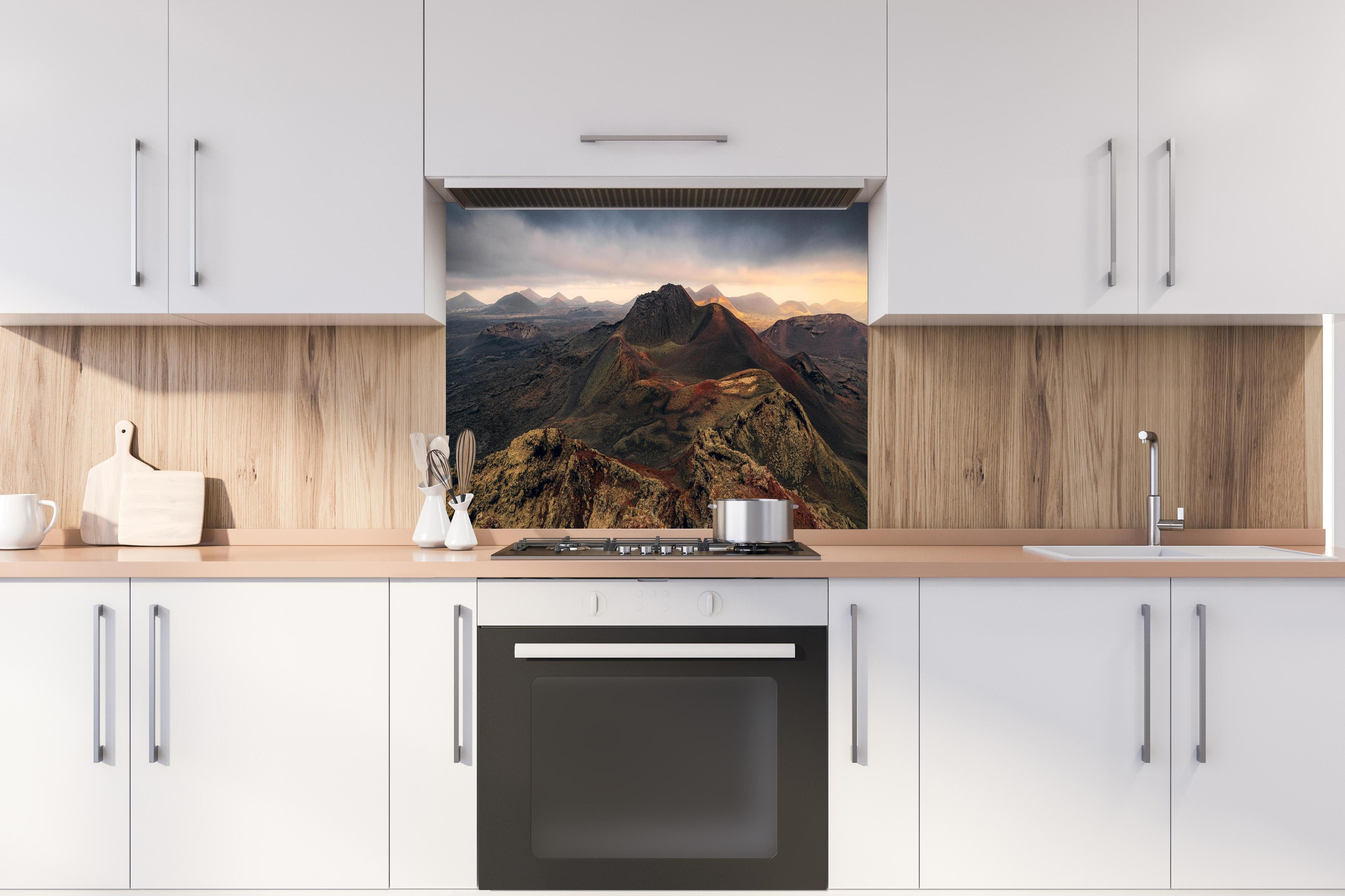 Spritzschutz - Panorama Vulkanberge unter dramatischem Himmel hinter einem Cerankochfeld zwischen Holz-Kochutensilien