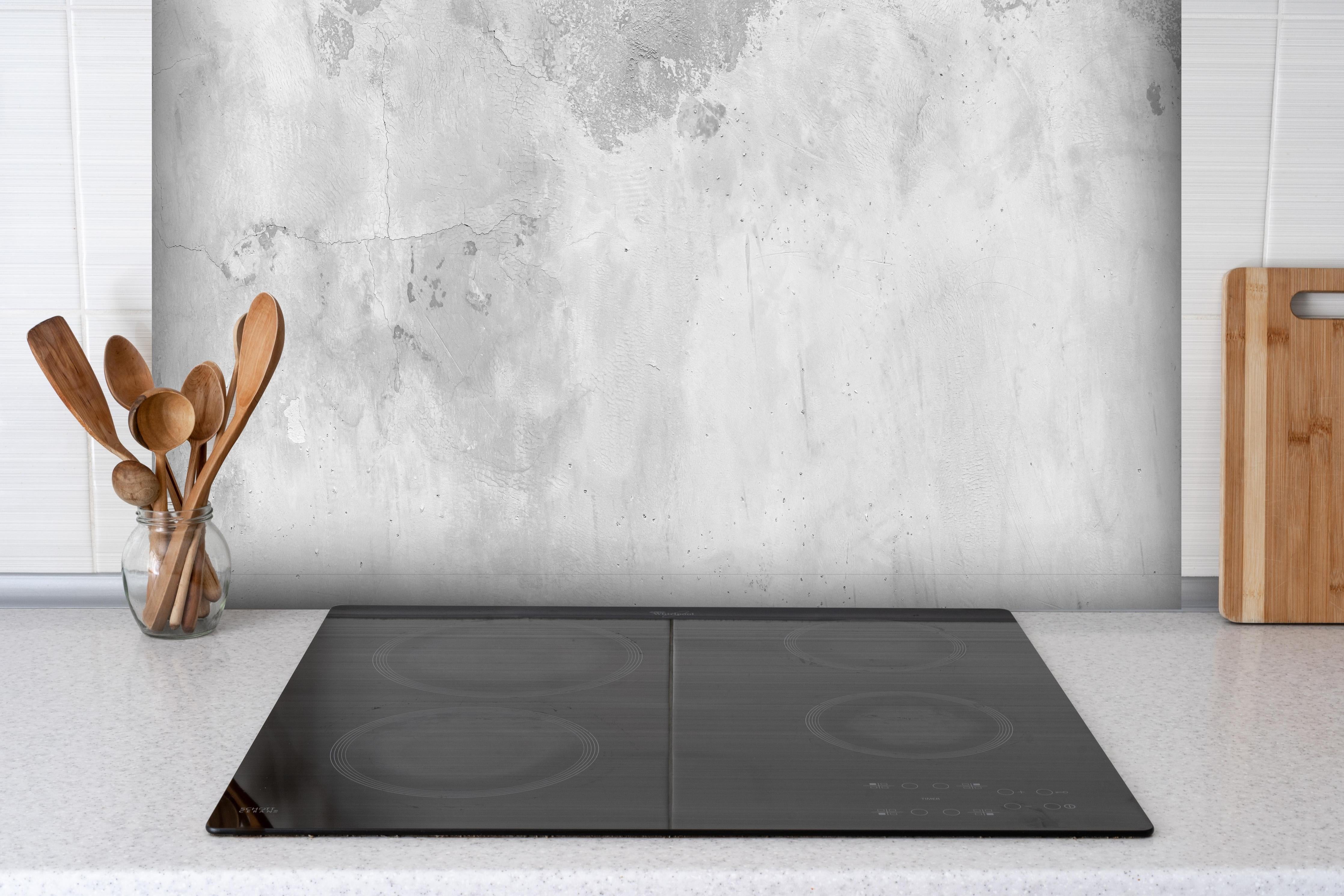 Spritzschutz - Panorama einer alten Betonwand hinter einem Cerankochfeld zwischen Holz-Kochutensilien