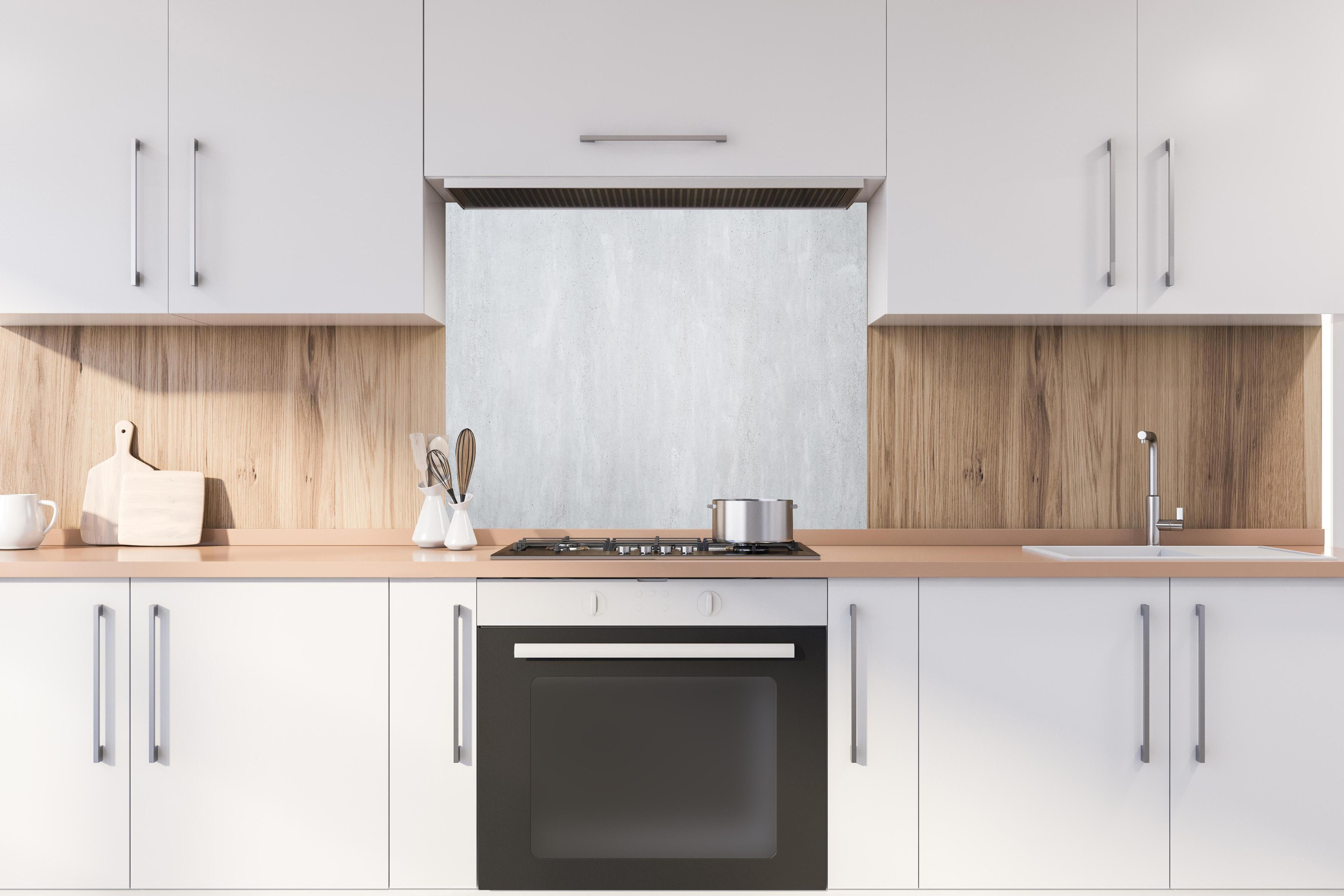 Spritzschutz - Panorama einer glatten grauen Betonwand hinter einem Cerankochfeld zwischen Holz-Kochutensilien