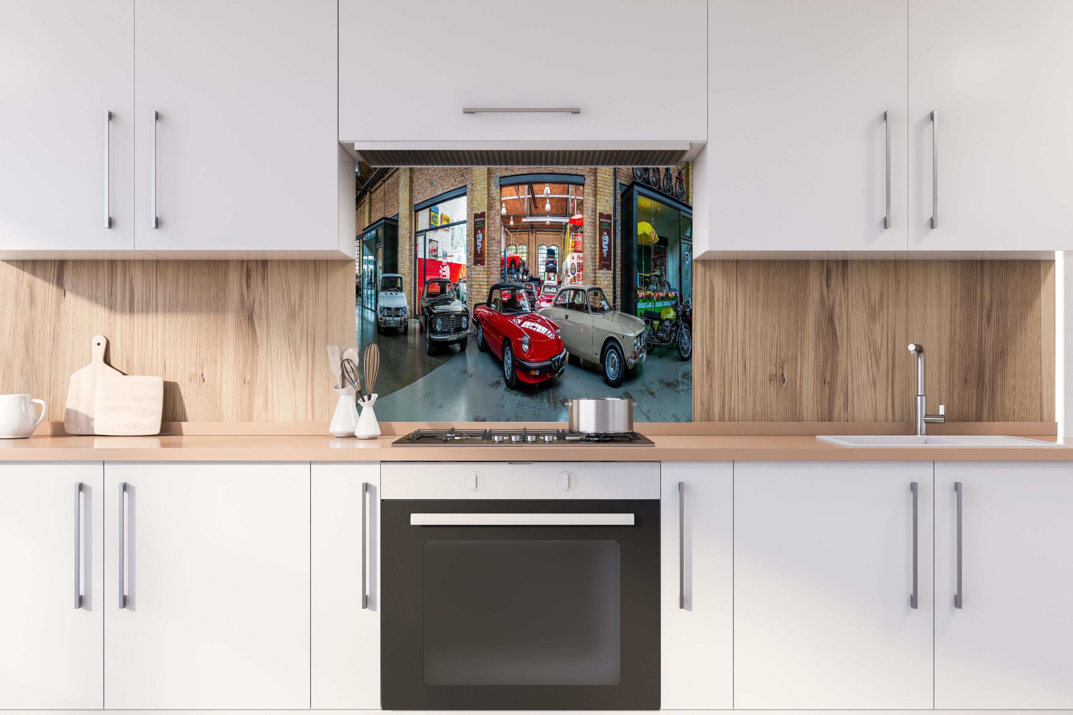 Spritzschutz - Panoramablick auf die Werkstatt der Classic Remise Berlin hinter einem Cerankochfeld zwischen Holz-Kochutensilien