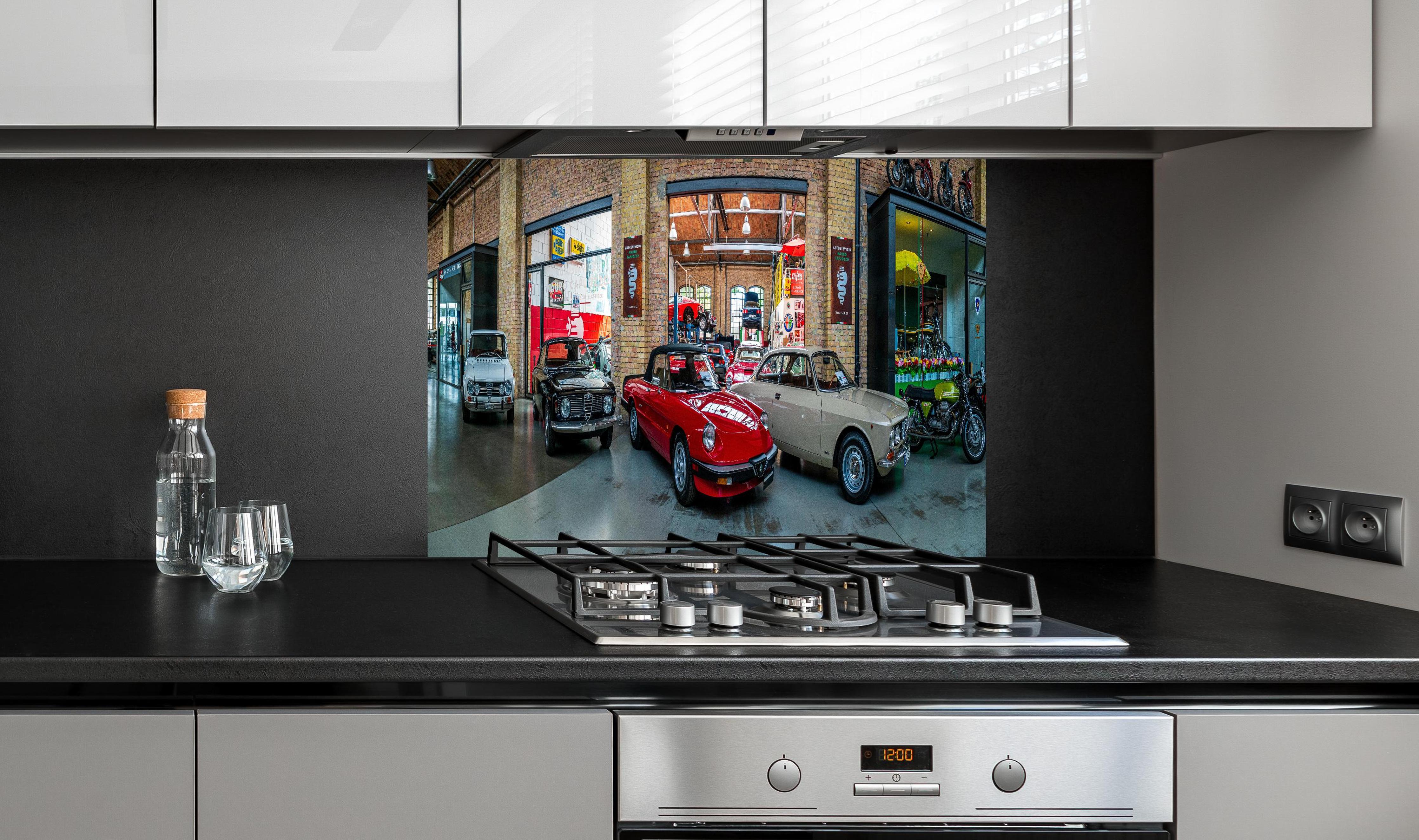 Spritzschutz - Panoramablick auf die Werkstatt der Classic Remise Berlin hinter einem Cerankochfeld zwischen Holz-Kochutensilien