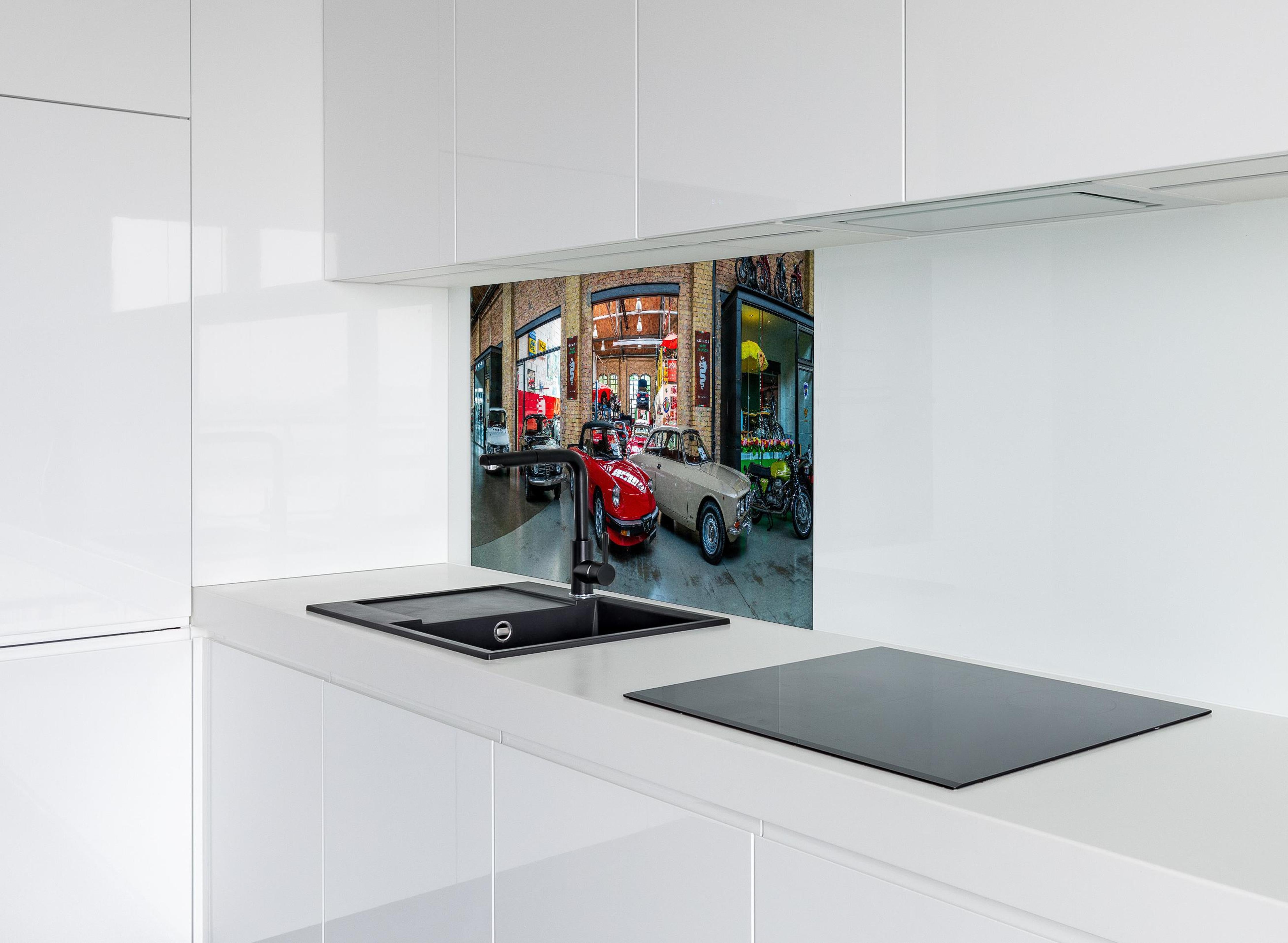 Spritzschutz - Panoramablick auf die Werkstatt der Classic Remise Berlin hinter einem Cerankochfeld zwischen Holz-Kochutensilien