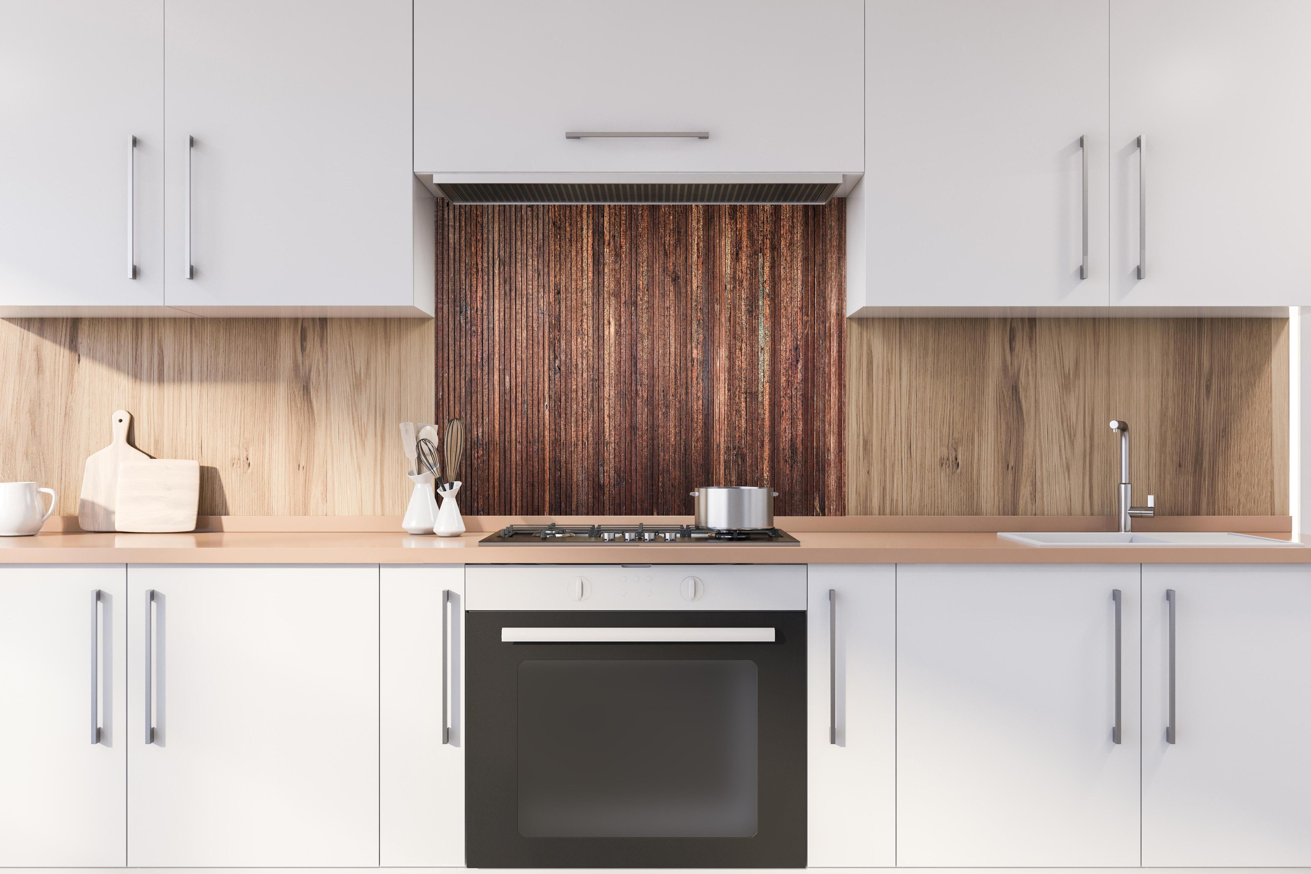 Spritzschutz - Panoramahintergrund aus vertikalen schmalen Holzplatten hinter einem Cerankochfeld zwischen Holz-Kochutensilien