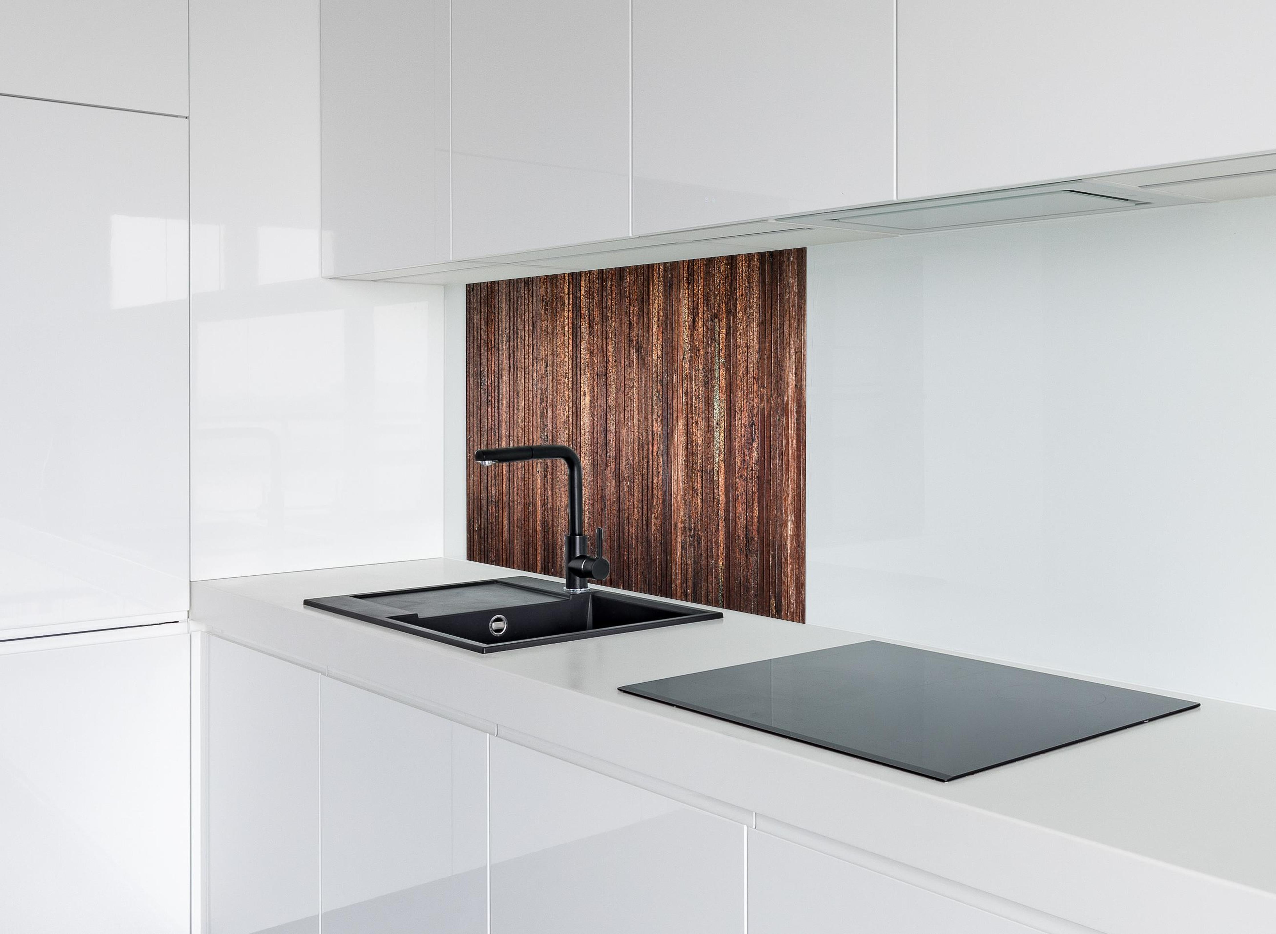 Spritzschutz - Panoramahintergrund aus vertikalen schmalen Holzplatten hinter einem Cerankochfeld zwischen Holz-Kochutensilien