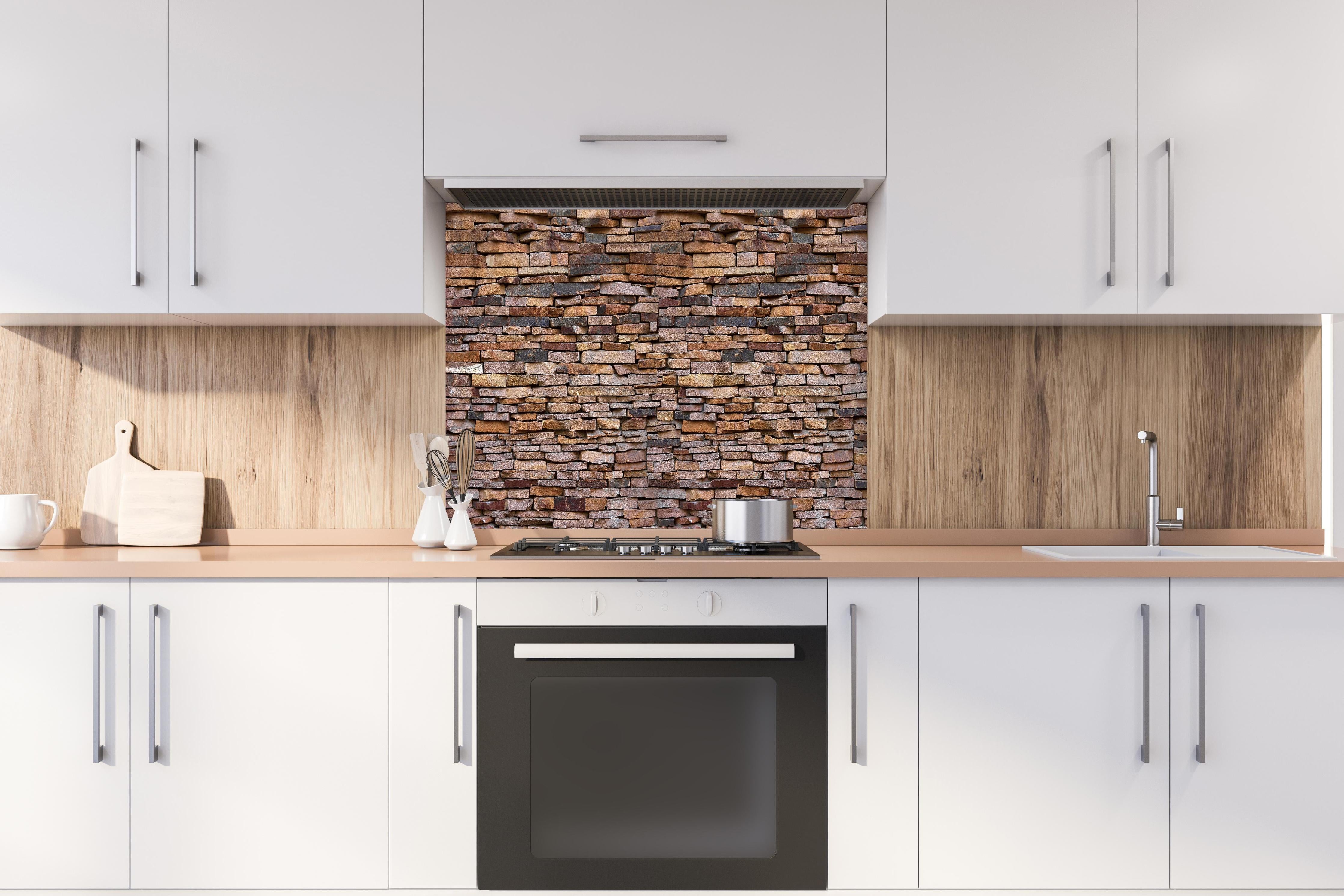 Spritzschutz - Panoramaplatte Granit hinter einem Cerankochfeld zwischen Holz-Kochutensilien